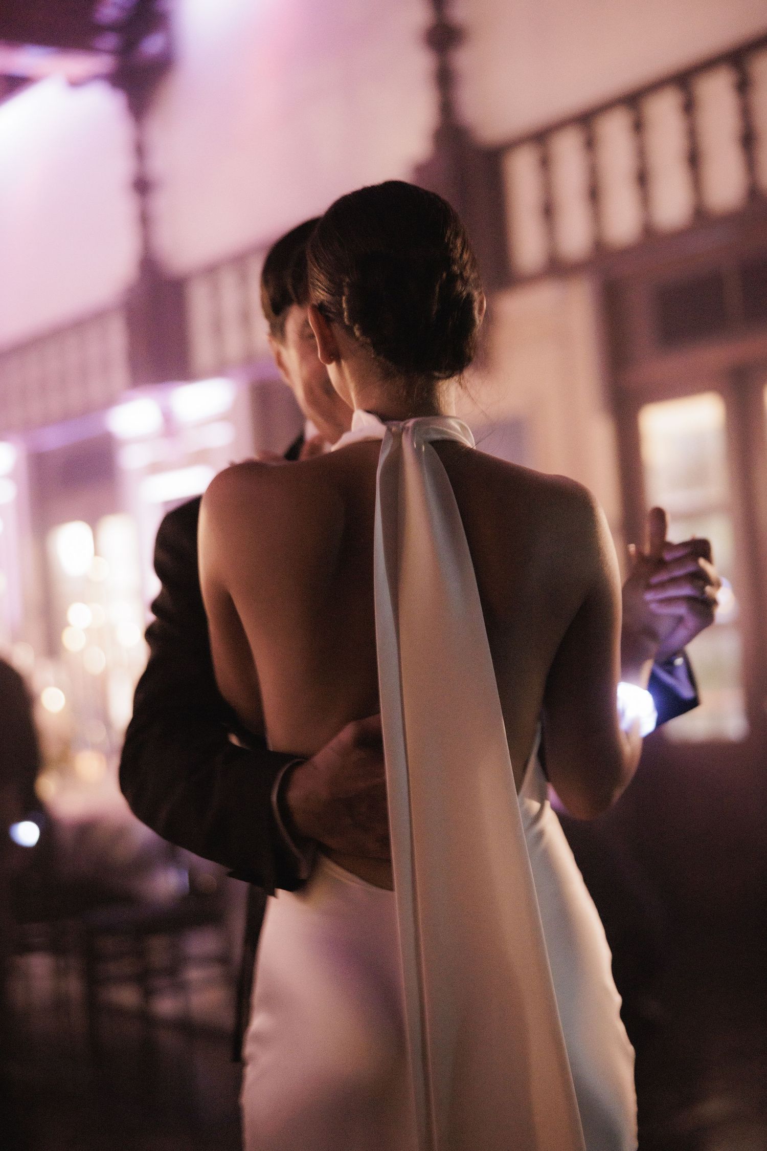 Romantic backlit silhouette of couple dancing at evening wedding reception.