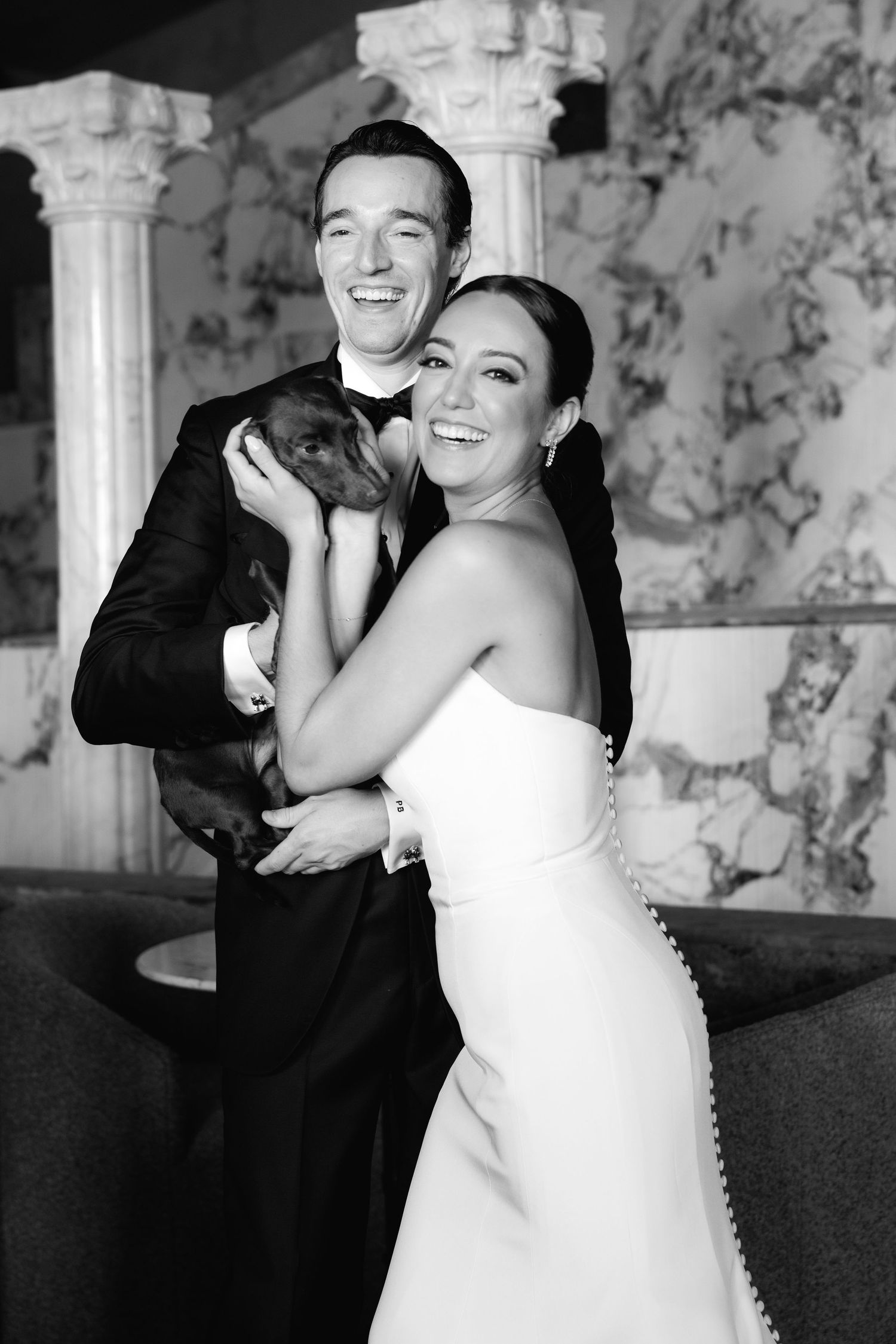 A joyful wedding atmosphere captured in black and white as couple shares intimate dance moves in elegant venue.