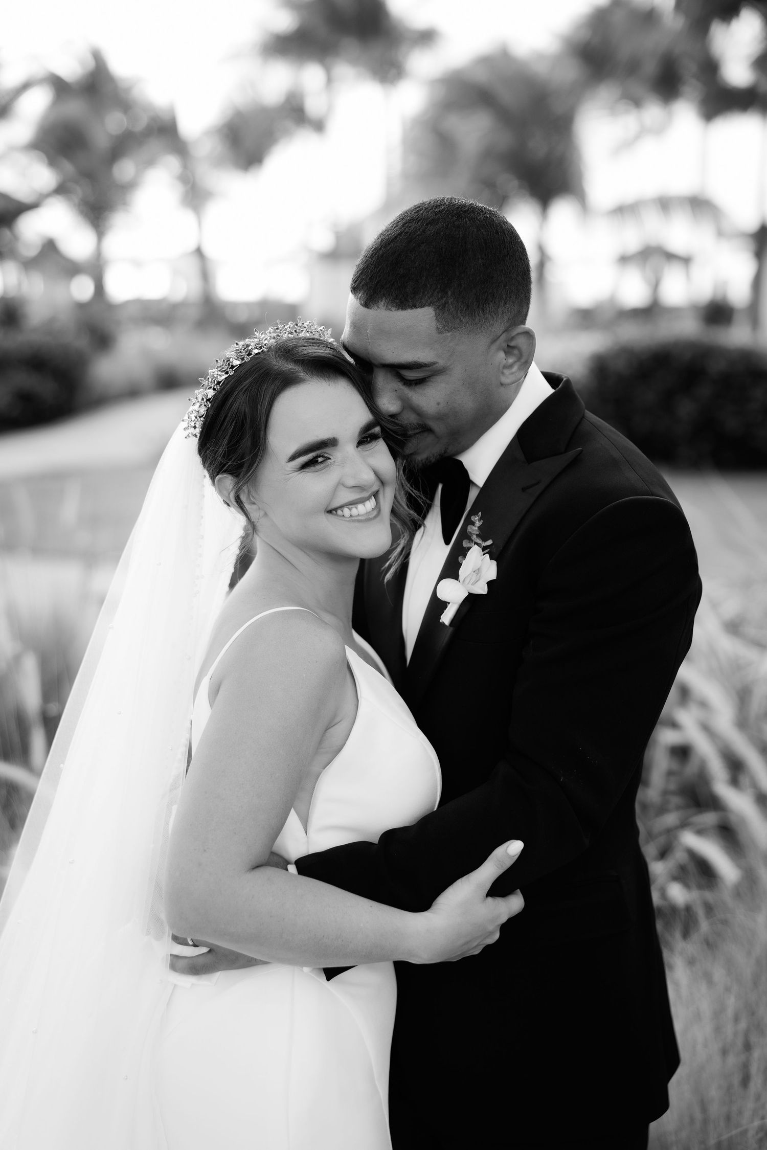 Black and white wedding photos show a couple sharing intimate moments outdoors in a romantic setting.