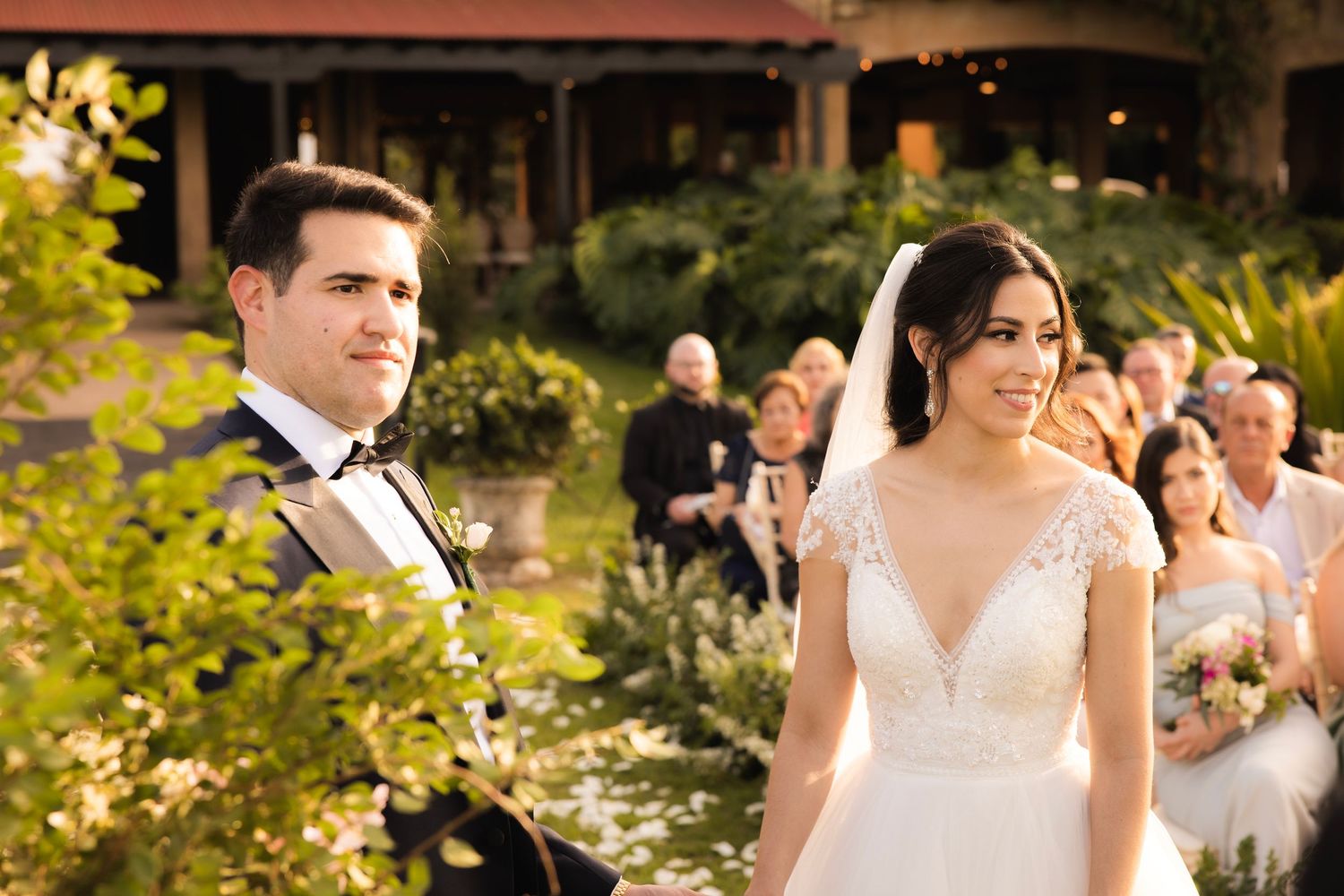 Golden hour wedding ceremony scene with guests seated outdoors.