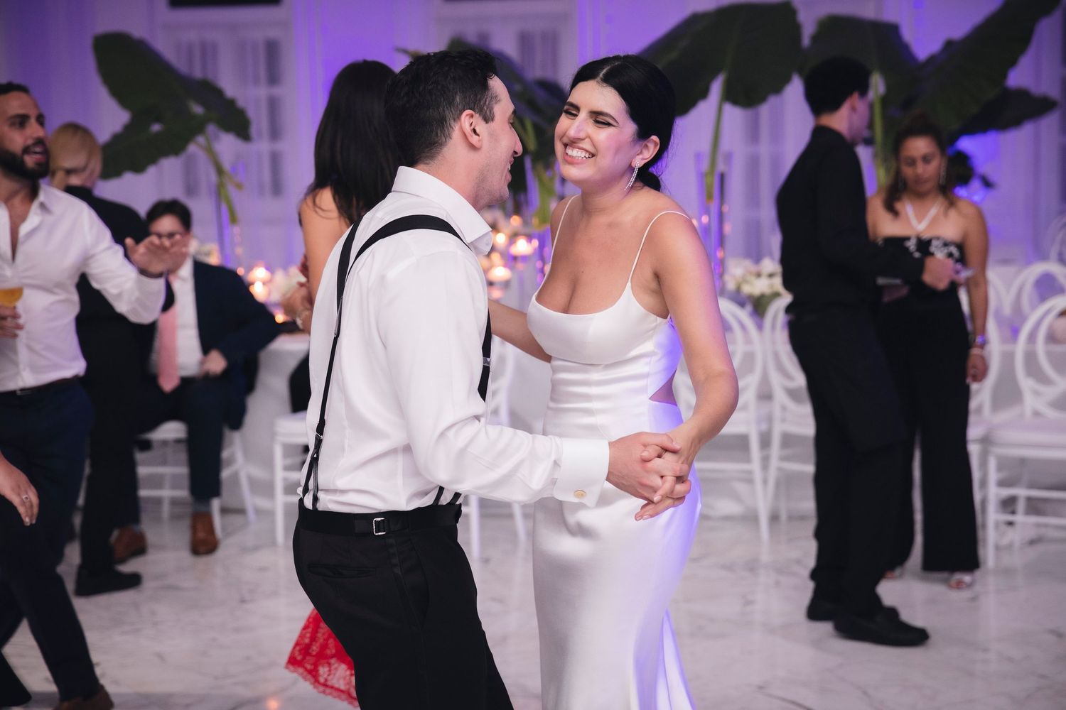 Dancers moving across an elegant ballroom floor with purple atmospheric lighting and decorative elements.