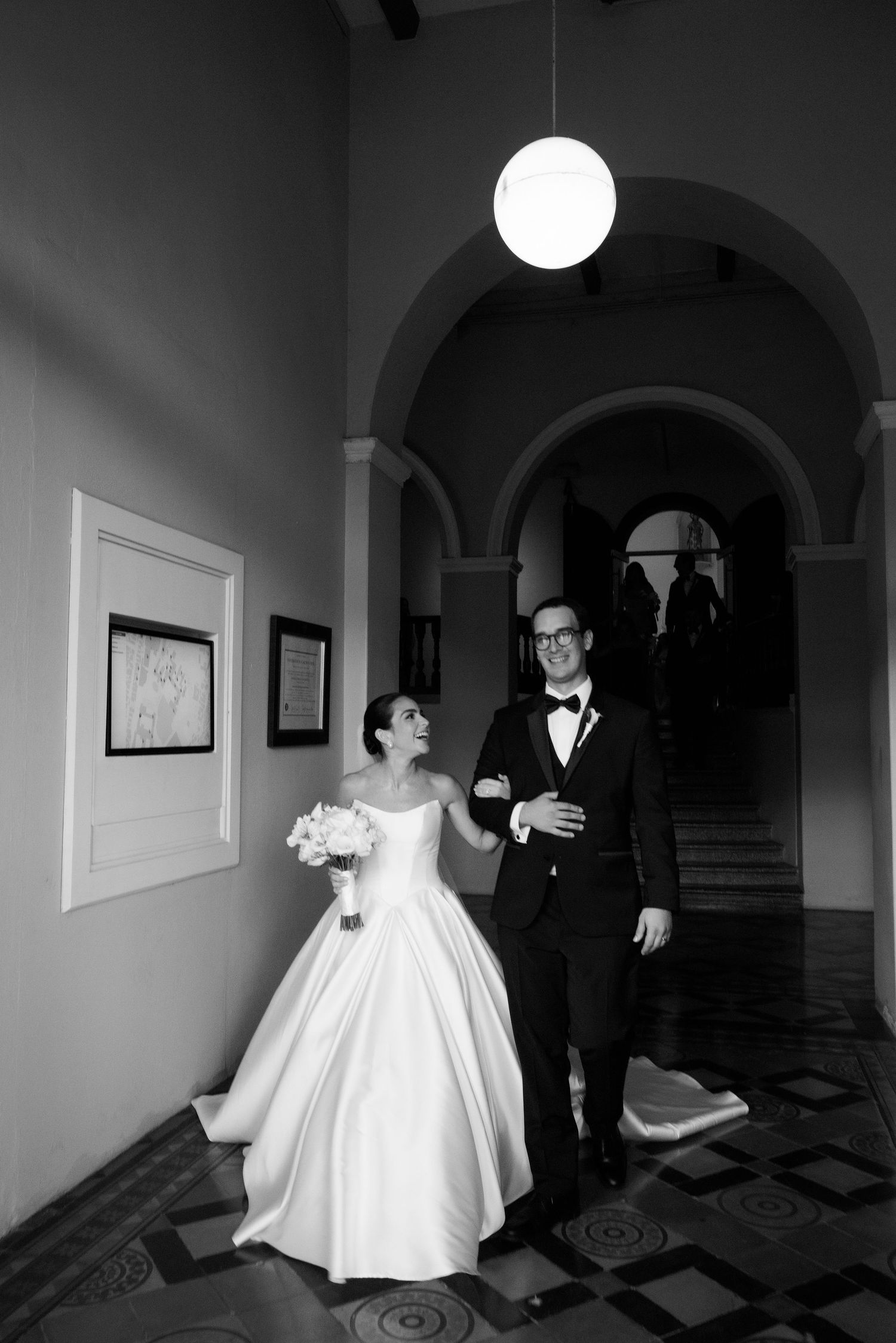 Black and white wedding photos in elegant arched hallway.