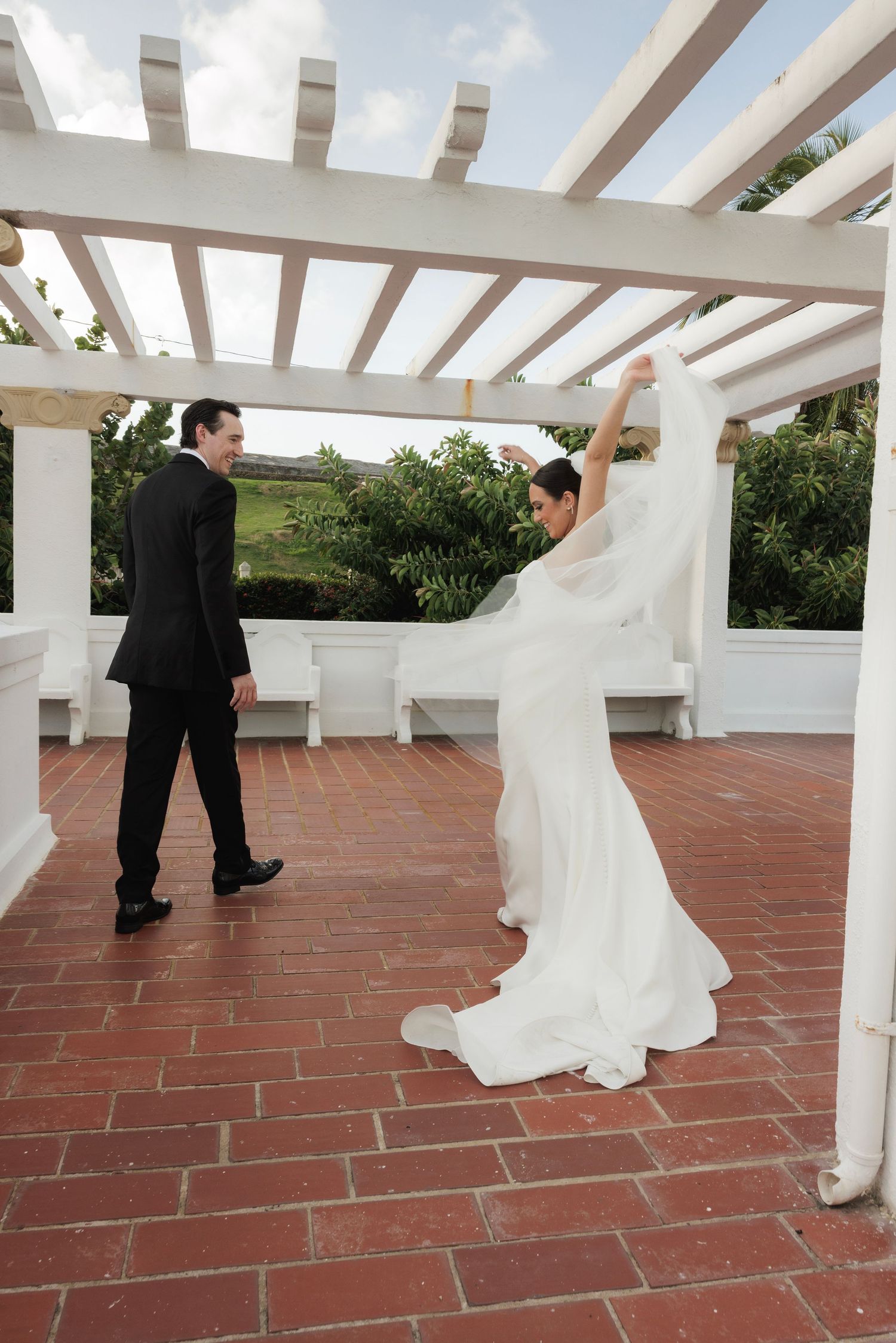 Elegant couple dancing on a terrace with white pergola and terracotta tile floor.