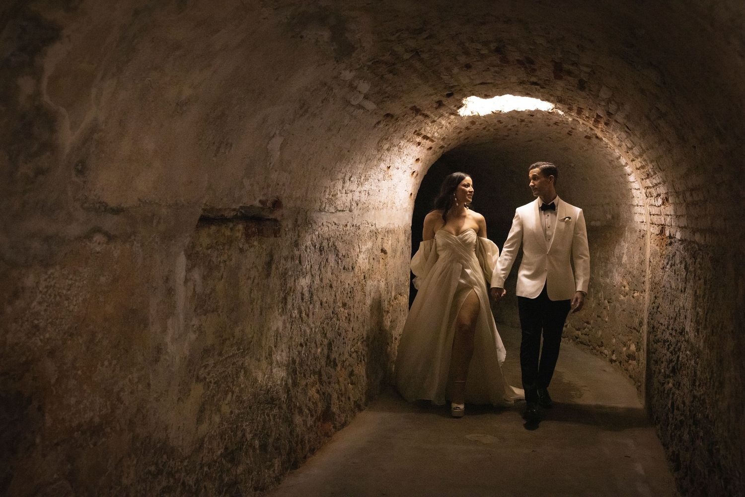 Atmospheric tunnel wedding photos with dramatic lighting and stone walls.