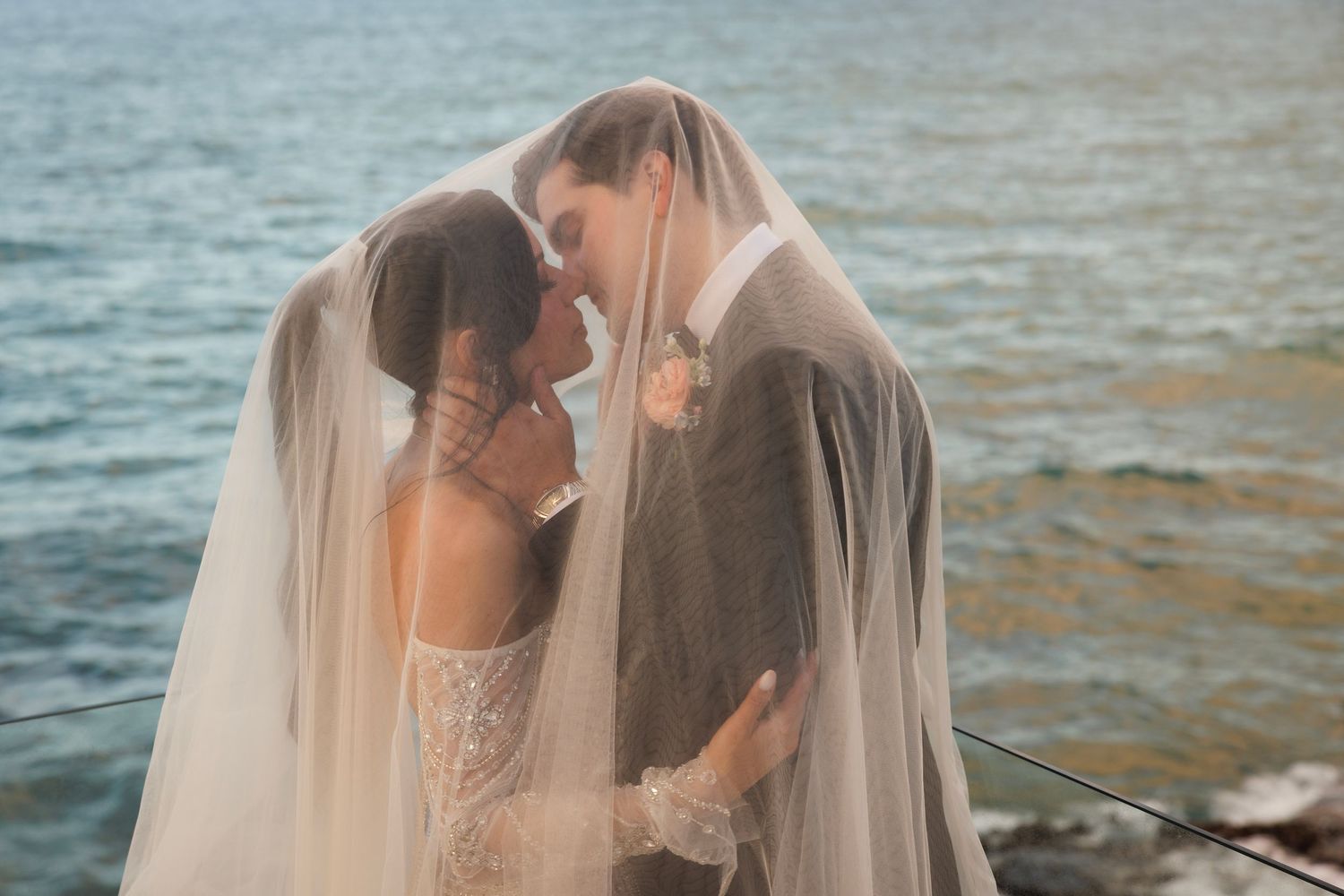 A couple in wedding attire embraces on a dock by the water during golden hour photography session.