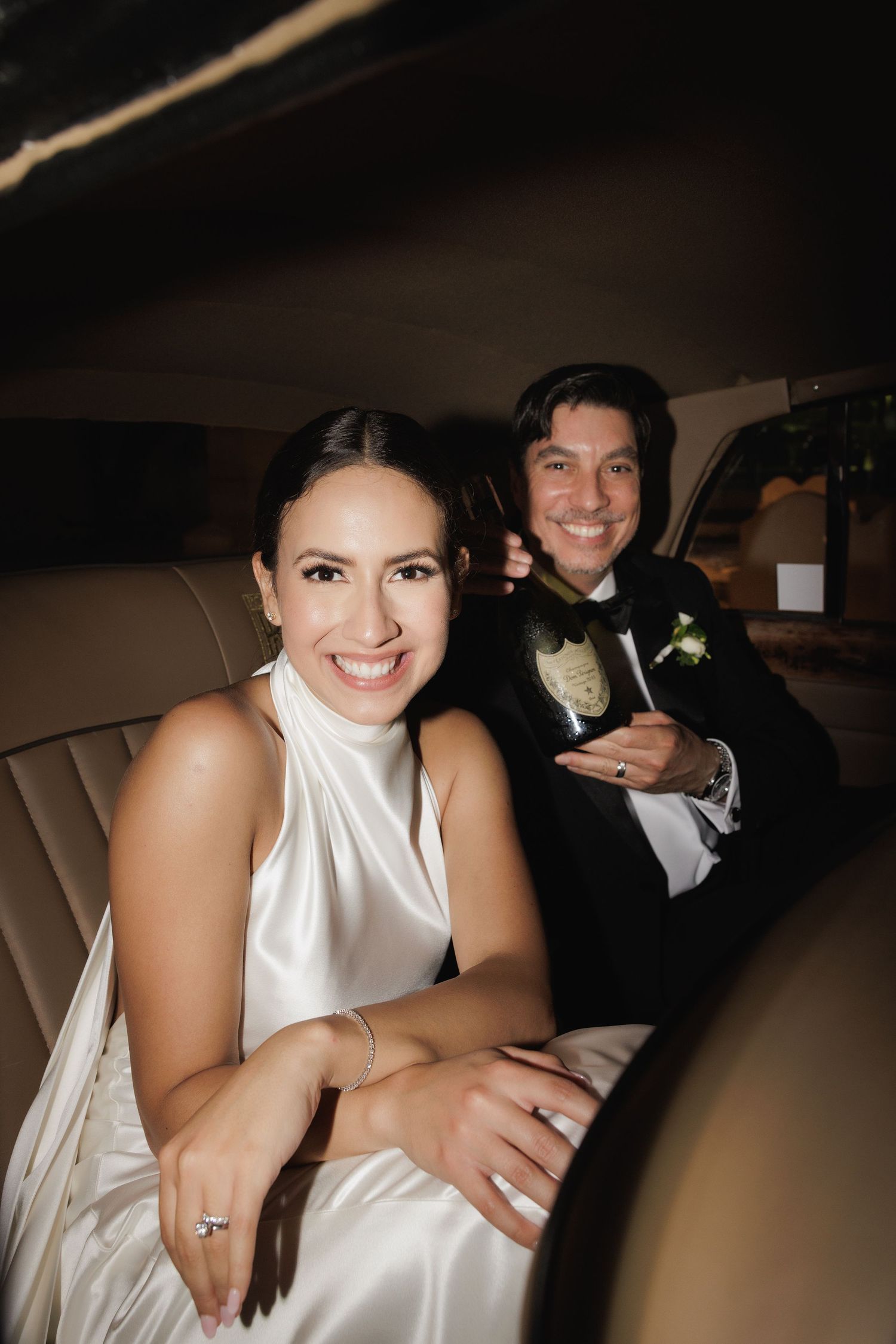 Newlyweds sharing intimate moment in back of luxury car after ceremony.
