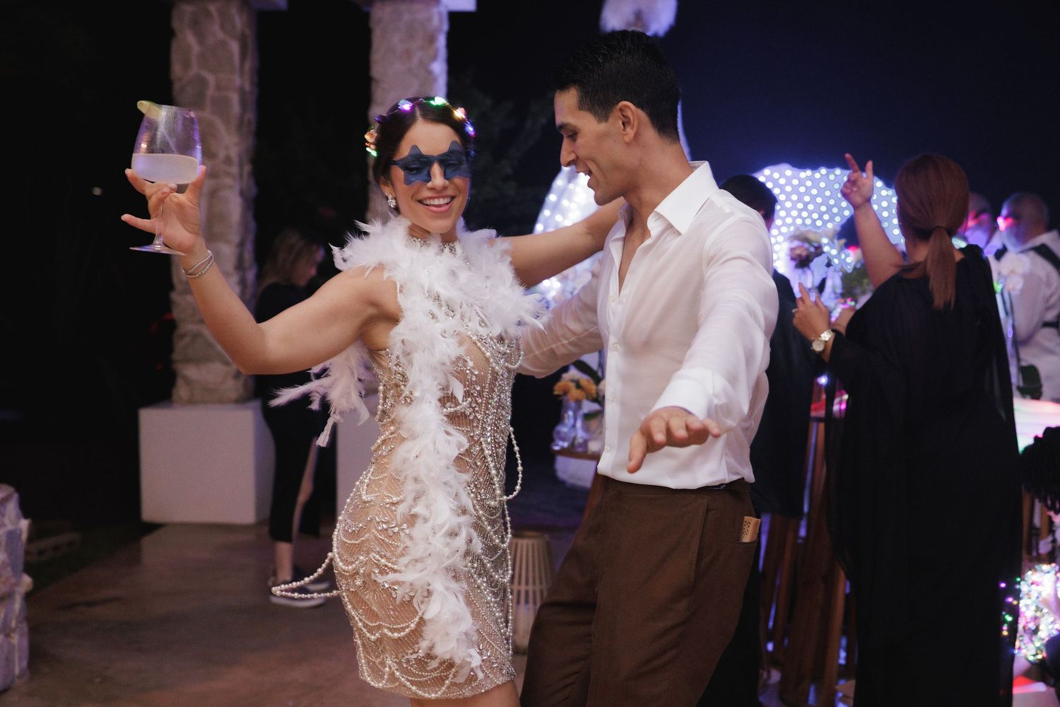 Wedding reception dance floor with guests celebrating under decorative lighting.