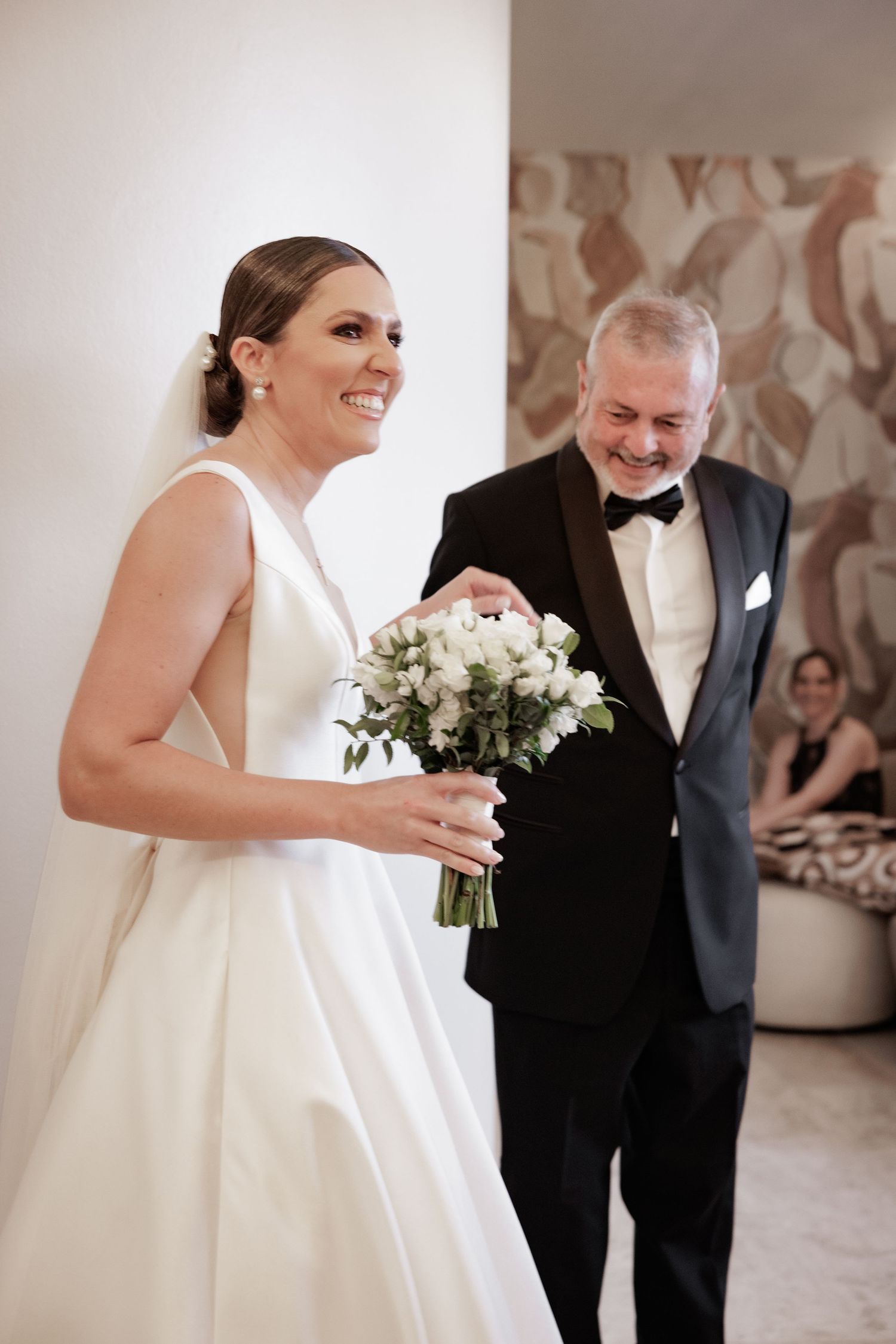 A joyful moment shared during a wedding celebration with elegant white florals and formal attire.
