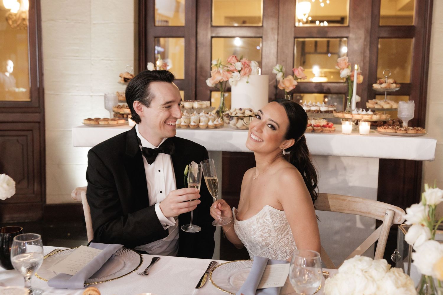 Newlywed couple shares a romantic dining moment at their reception table with candlelit decor.