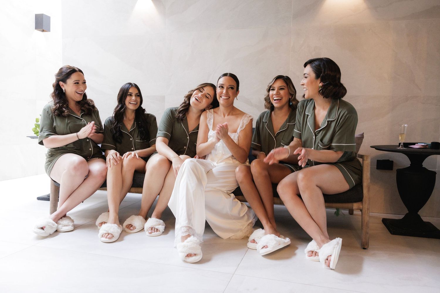 Group sitting together on a minimalist white floor wearing casual loungewear in pastel and neutral tones.