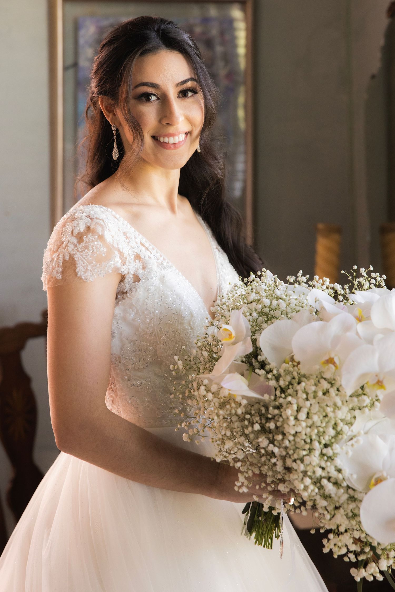 Elegant bridal portrait with white orchid and baby's breath bouquet in warm lighting.