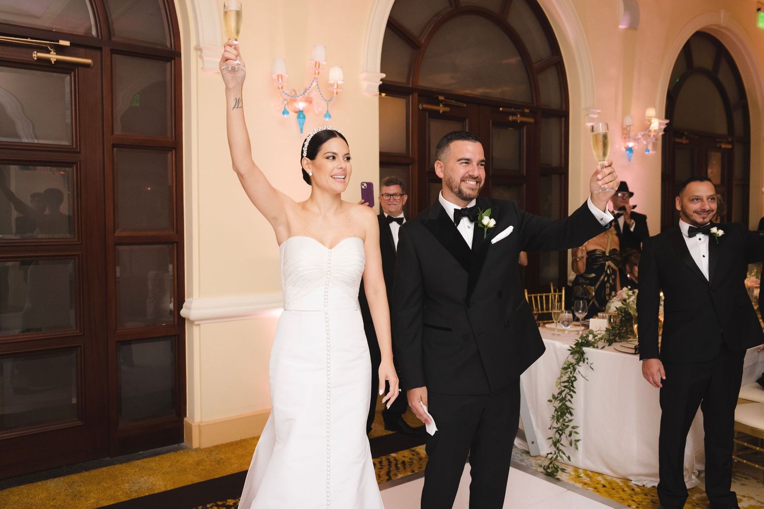 A celebratory wedding moment with a couple raising their hands in joy as they exit their ceremony together.