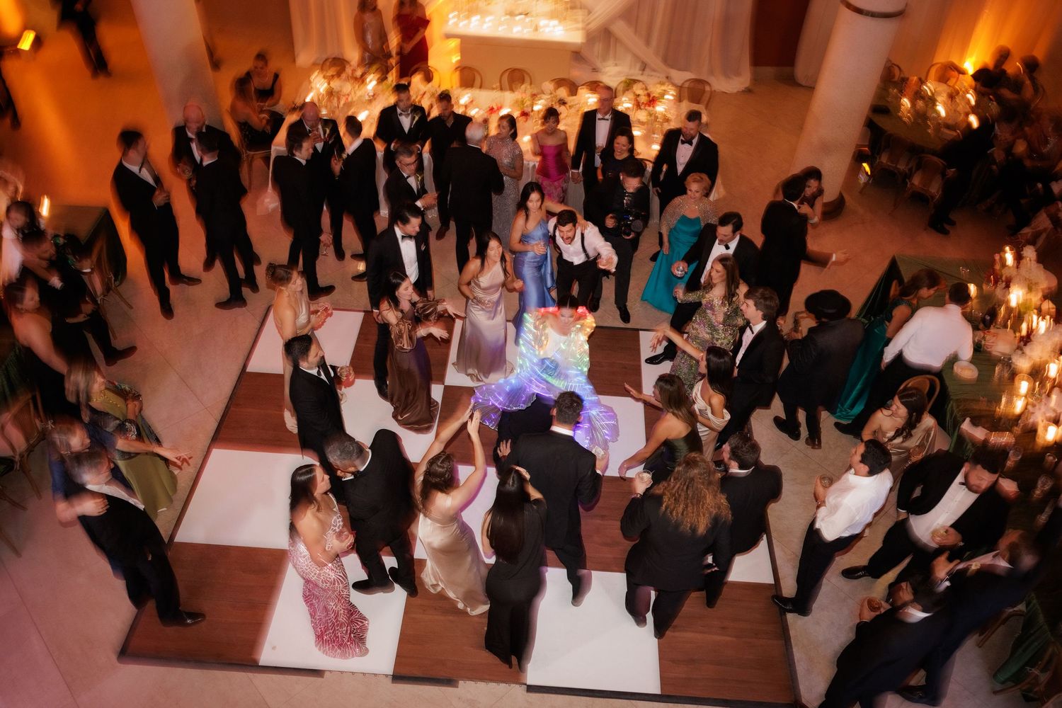An overhead view of wedding guests dancing on a black and white checkered dance floor.