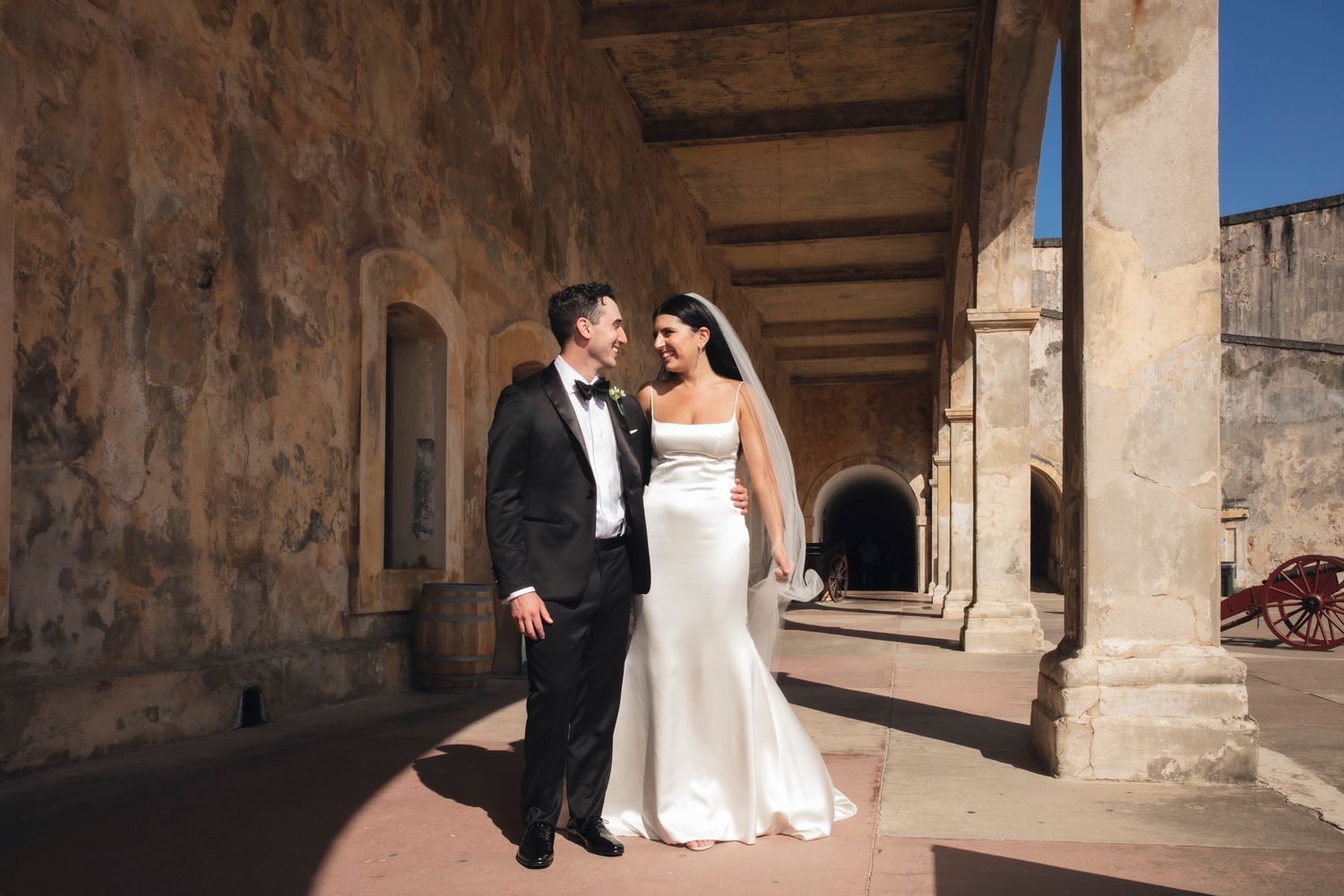 Wedding couple photographed in rustic stone arches and corridors of historic architecture.