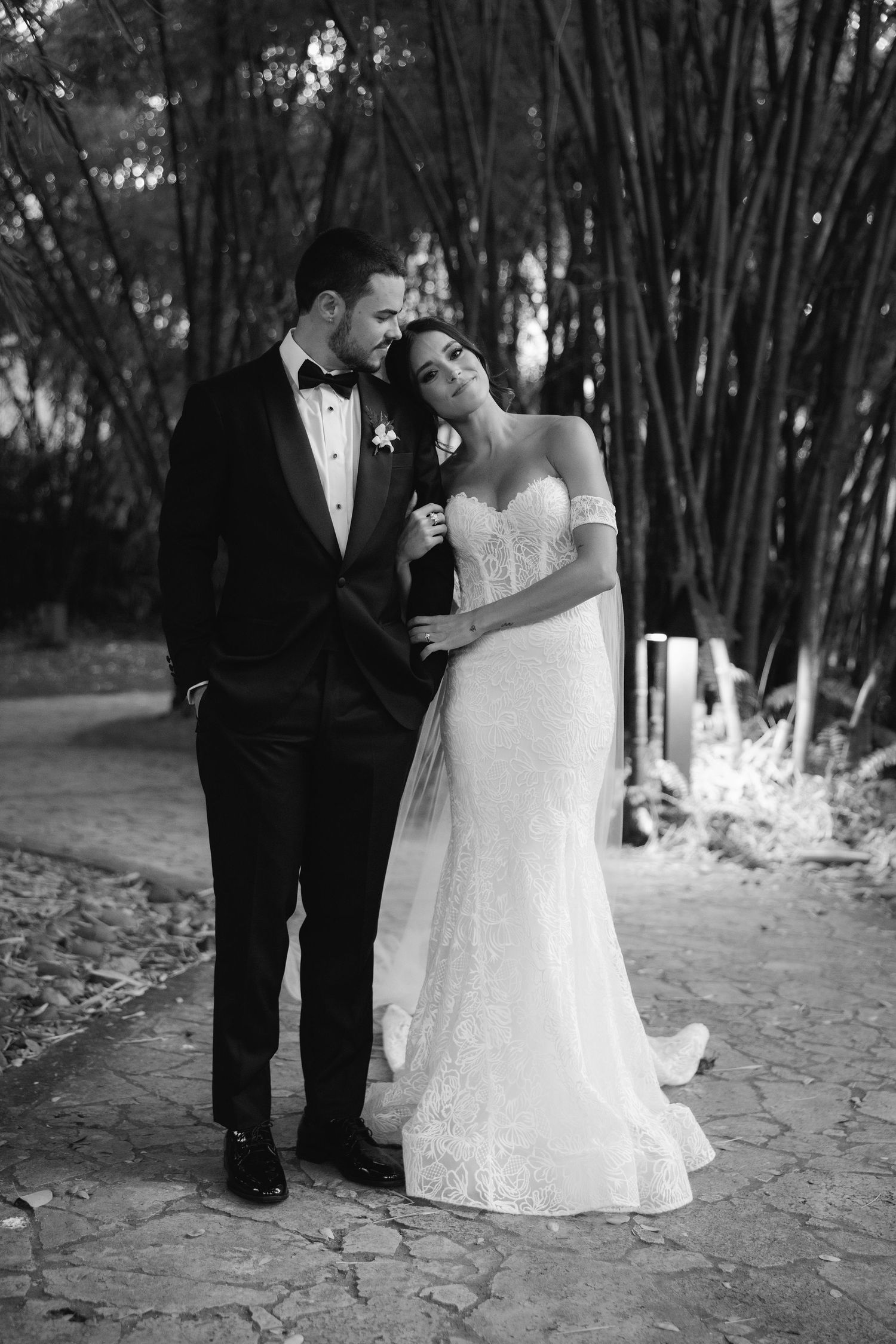 Black and white wedding portraits capture intimate moments between newlyweds in a wooded setting.