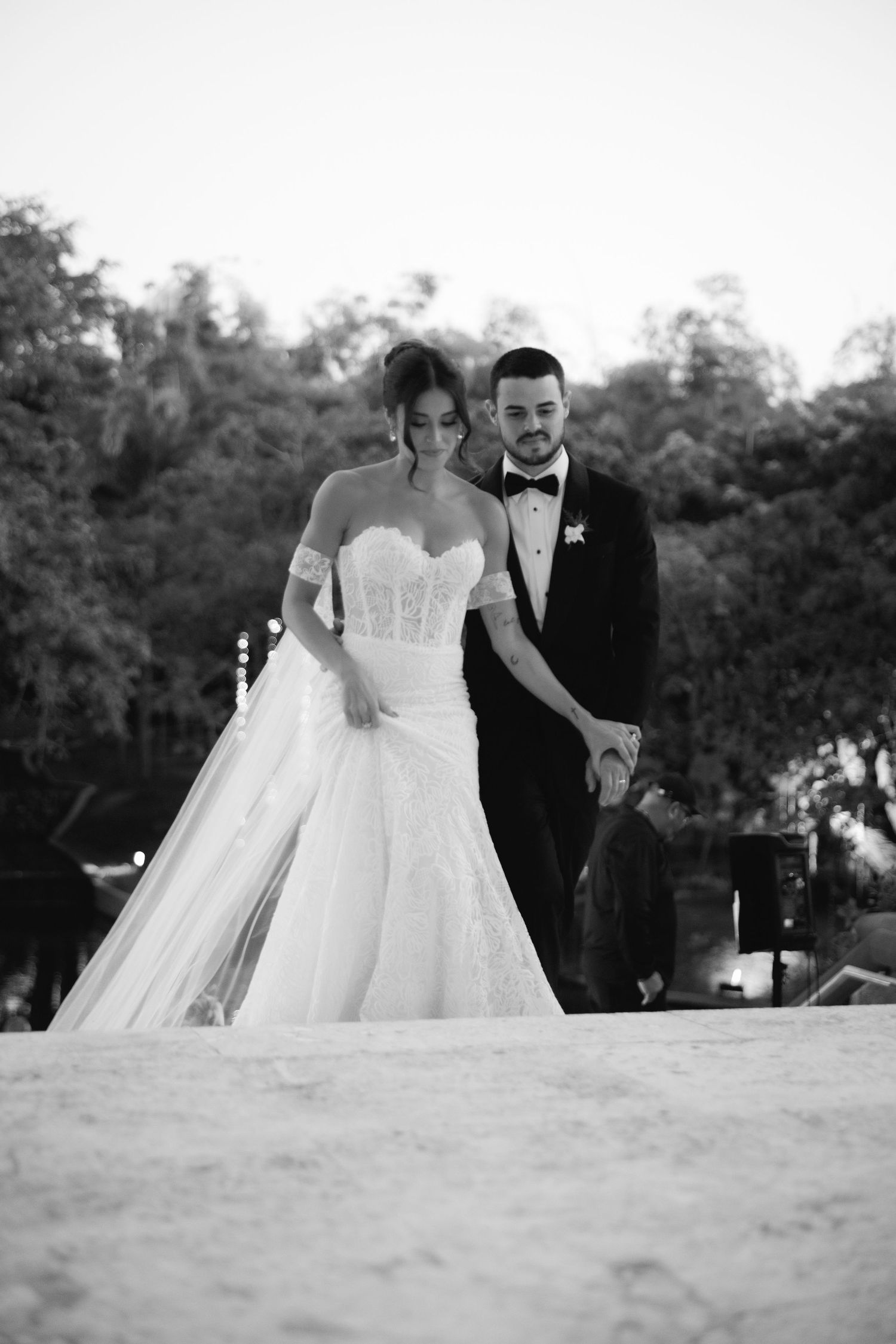 A classic black and white wedding portrait of a couple in formal attire on an outdoor terrace.