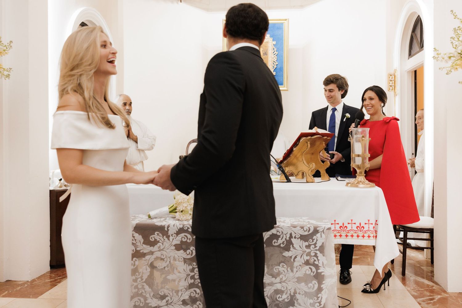 Elegant wedding scene in light-filled hallway with formal attire and decorative elements in warm tones.