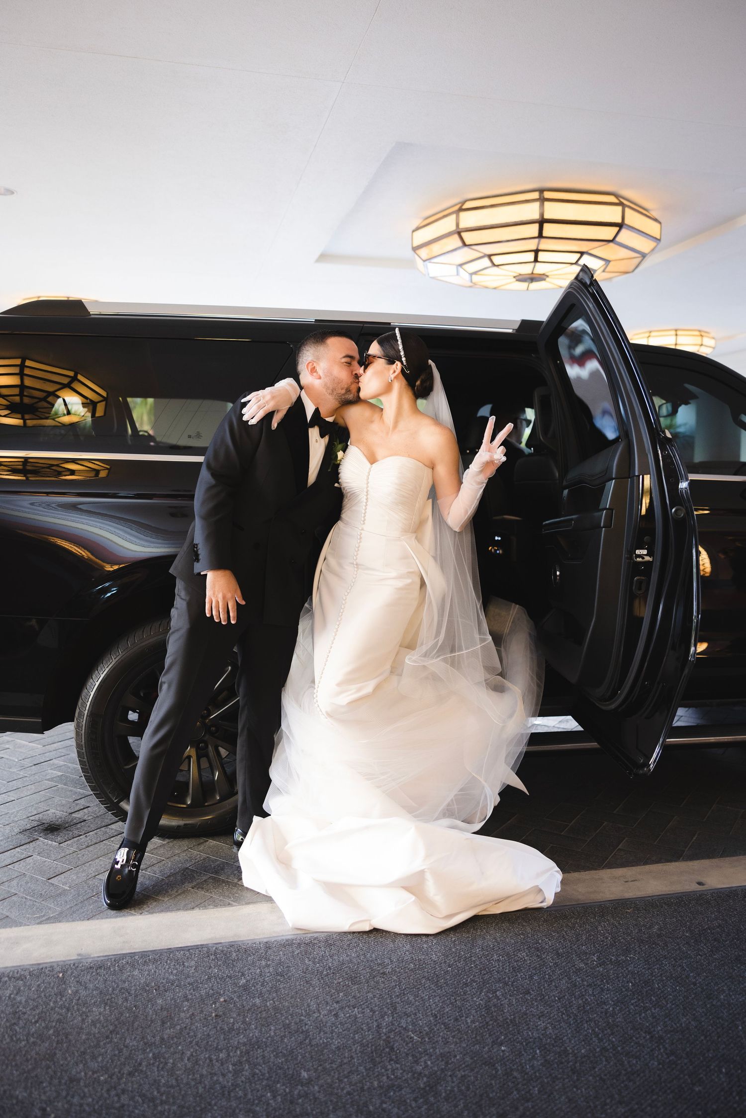 A wedding sequence showing a couple getting into a black limousine or luxury car as the bride's white dress flows elegantly.