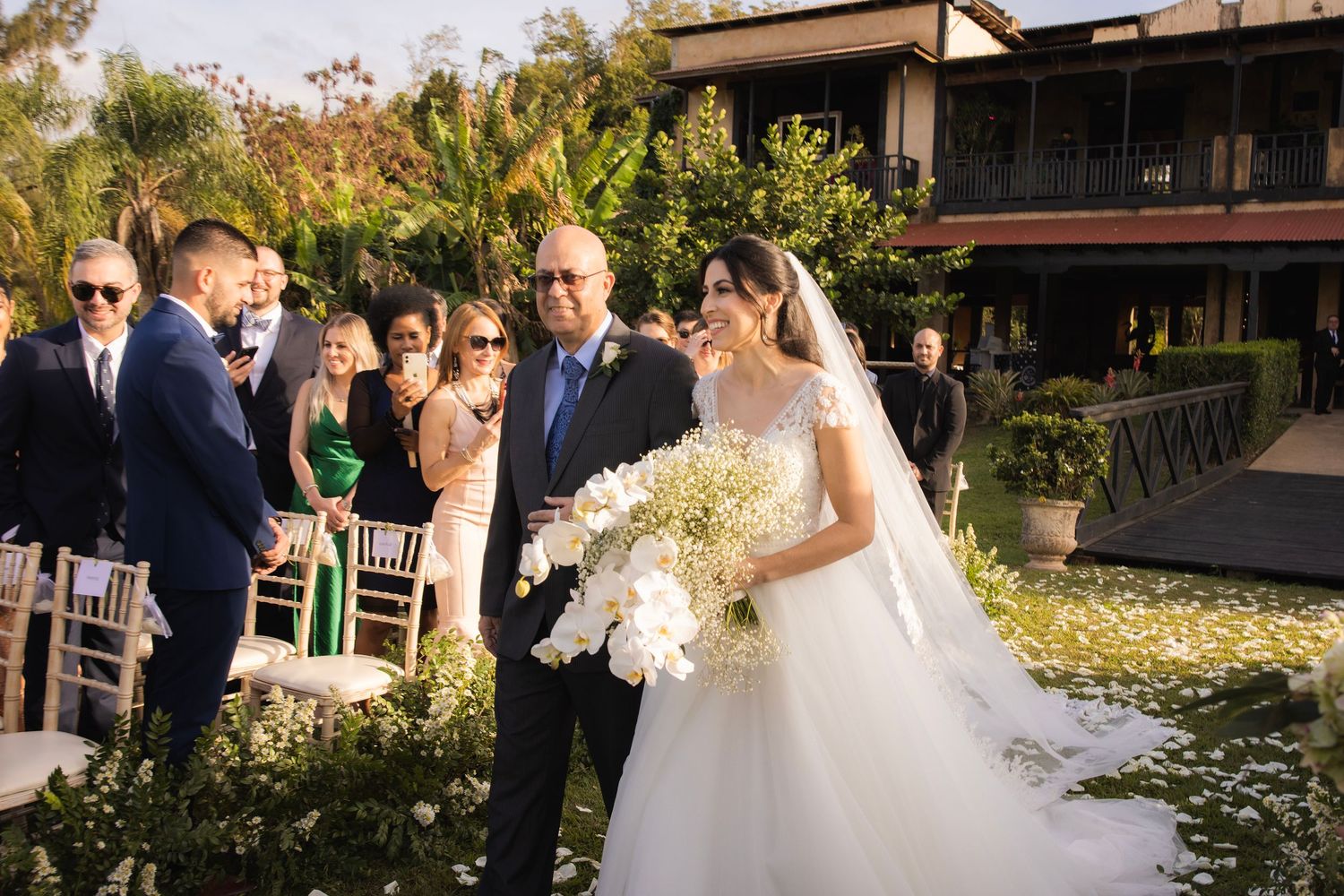 Wedding reception in progress at an outdoor venue with guests mingling in golden sunlight.