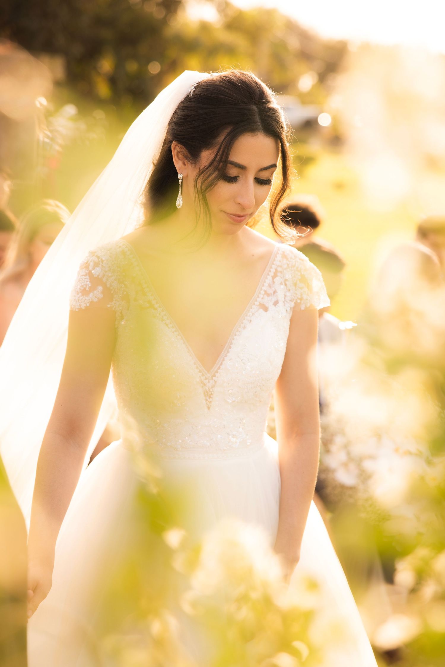 Ethereal sunlit bridal portrait through delicate foliage creating a dreamy golden hour effect.