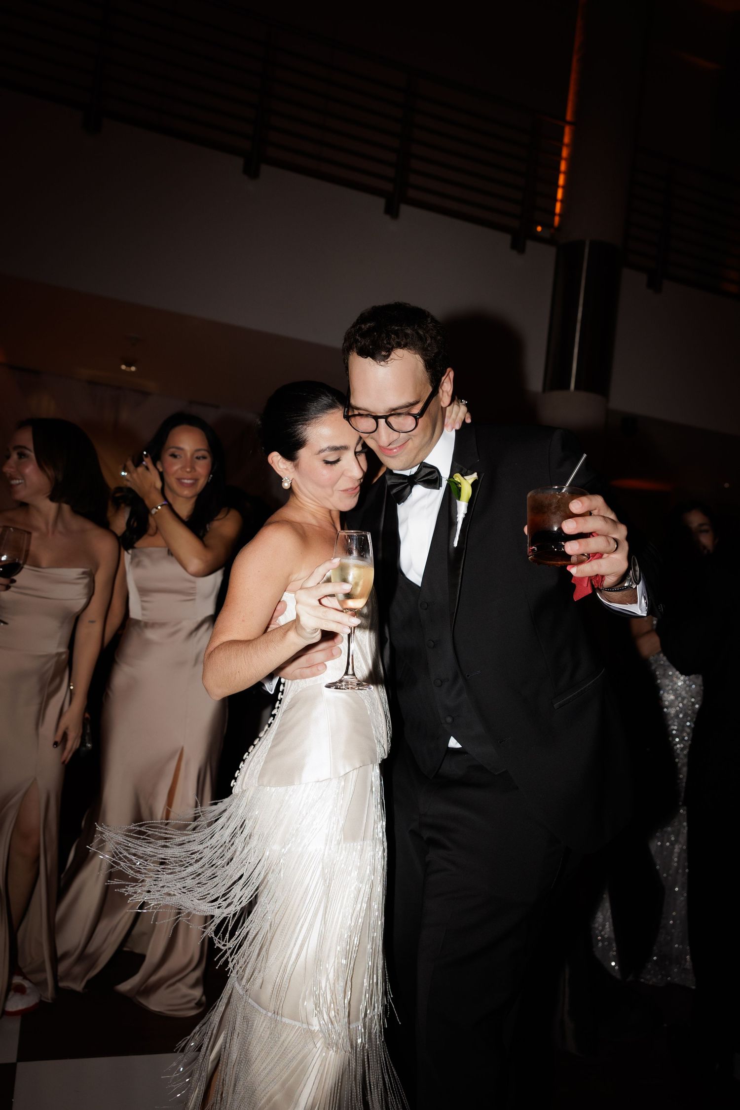 Couple sharing an intimate dance moment at their wedding reception with guests in the background.