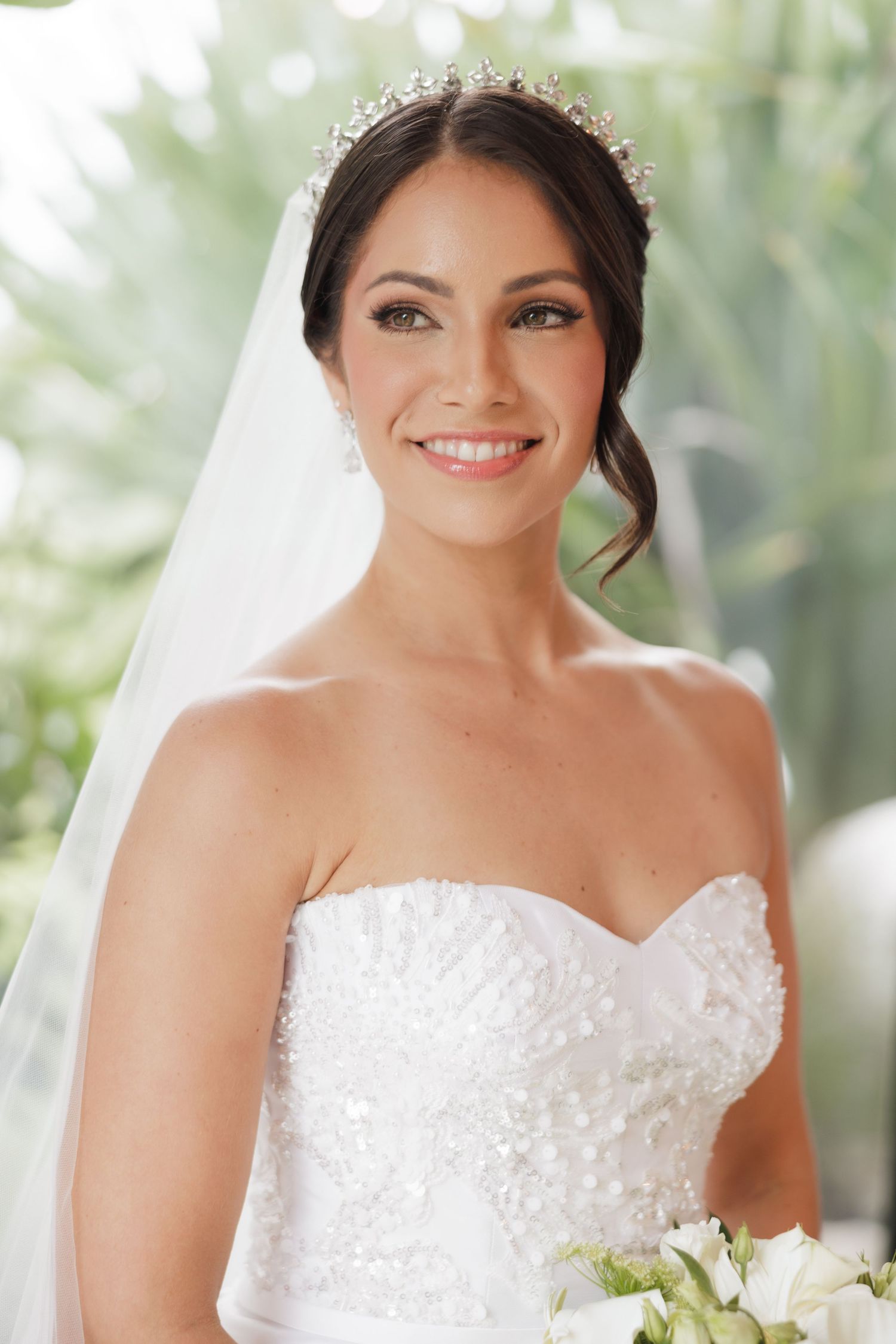 A strapless wedding dress with intricate beading and sweetheart neckline paired with a crystal tiara and veil.