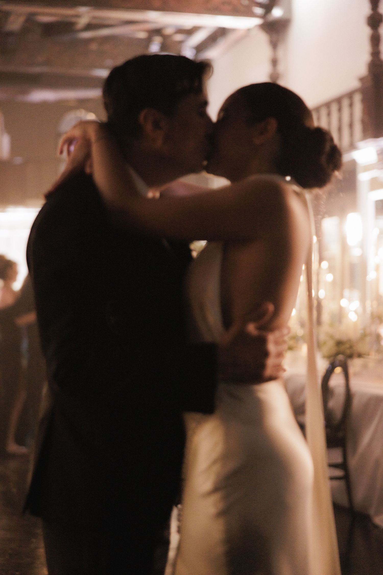 A romantic soft-focus photograph of a couple's first dance at their wedding reception.