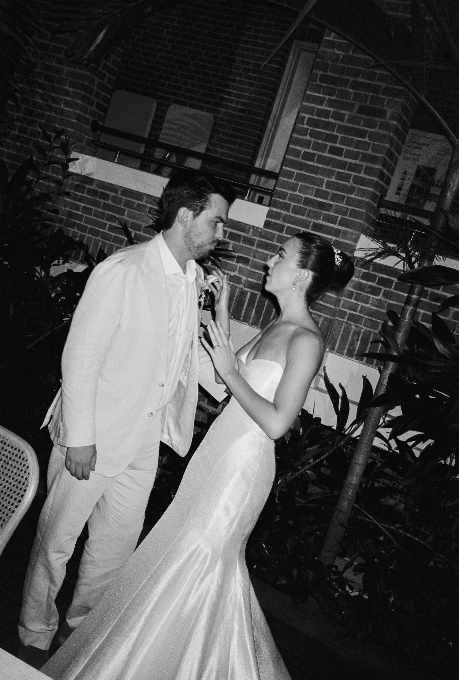 Black and white photo of a bride and groom sharing a romantic moment at their wedding reception.