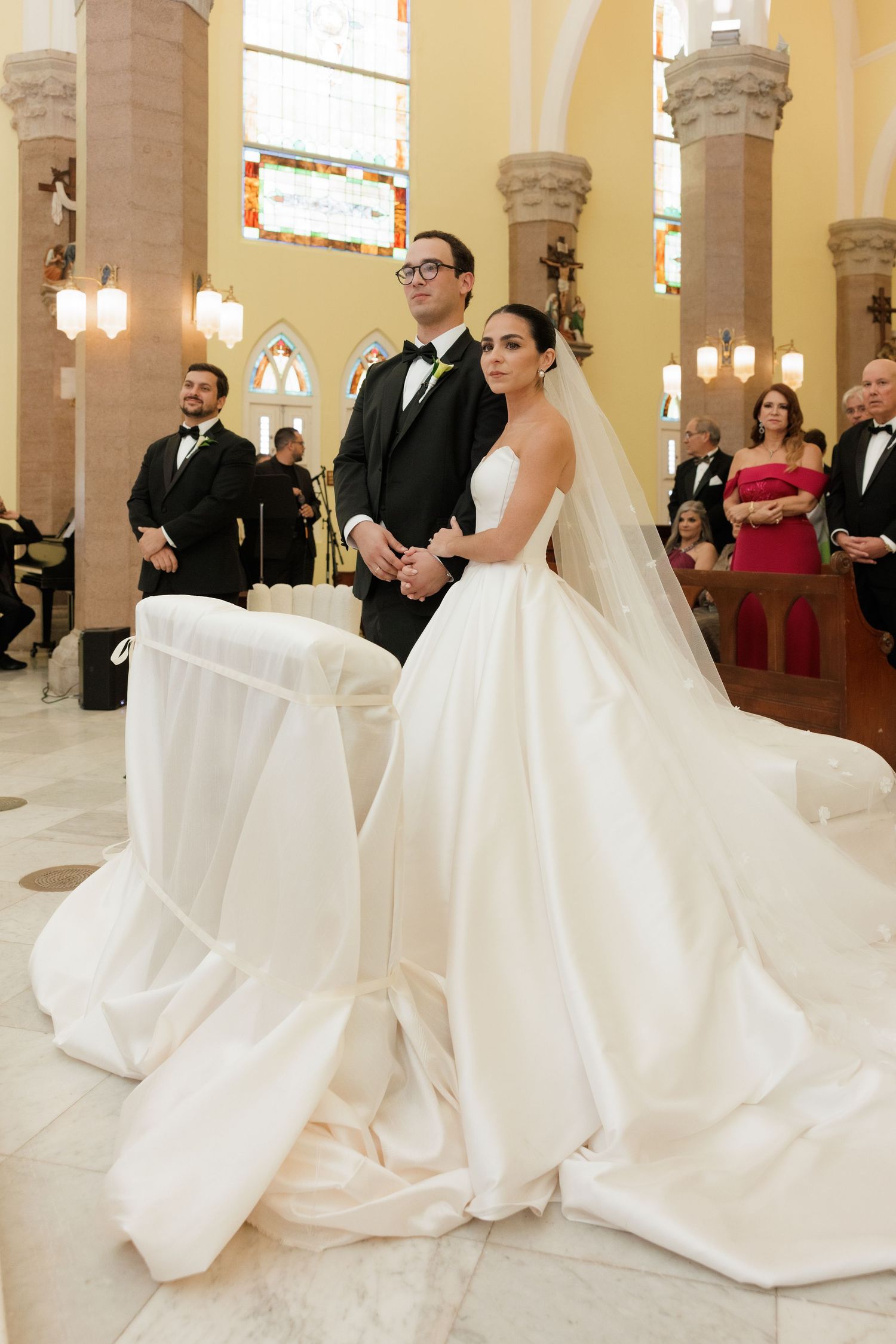 Wedding ceremony in a traditional church with stained glass windows and stone columns.