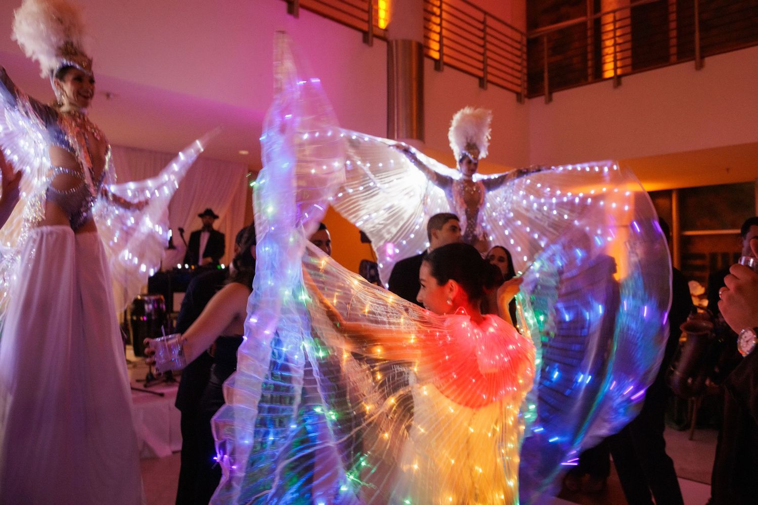 Performers with glowing LED wings create a magical light show on the dance floor.