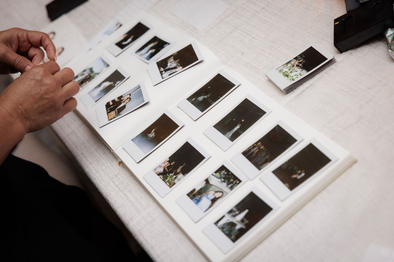 A collection of vintage photographs arranged in a sequence on a white surface being examined by someone's hands.