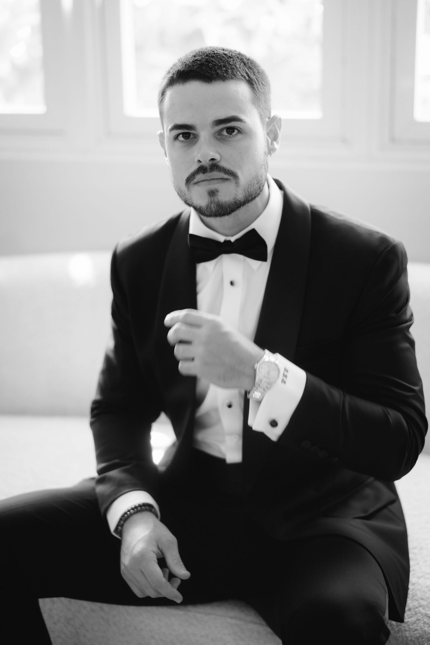 Black and white portraits of groom in tuxedo showing playful expressions.