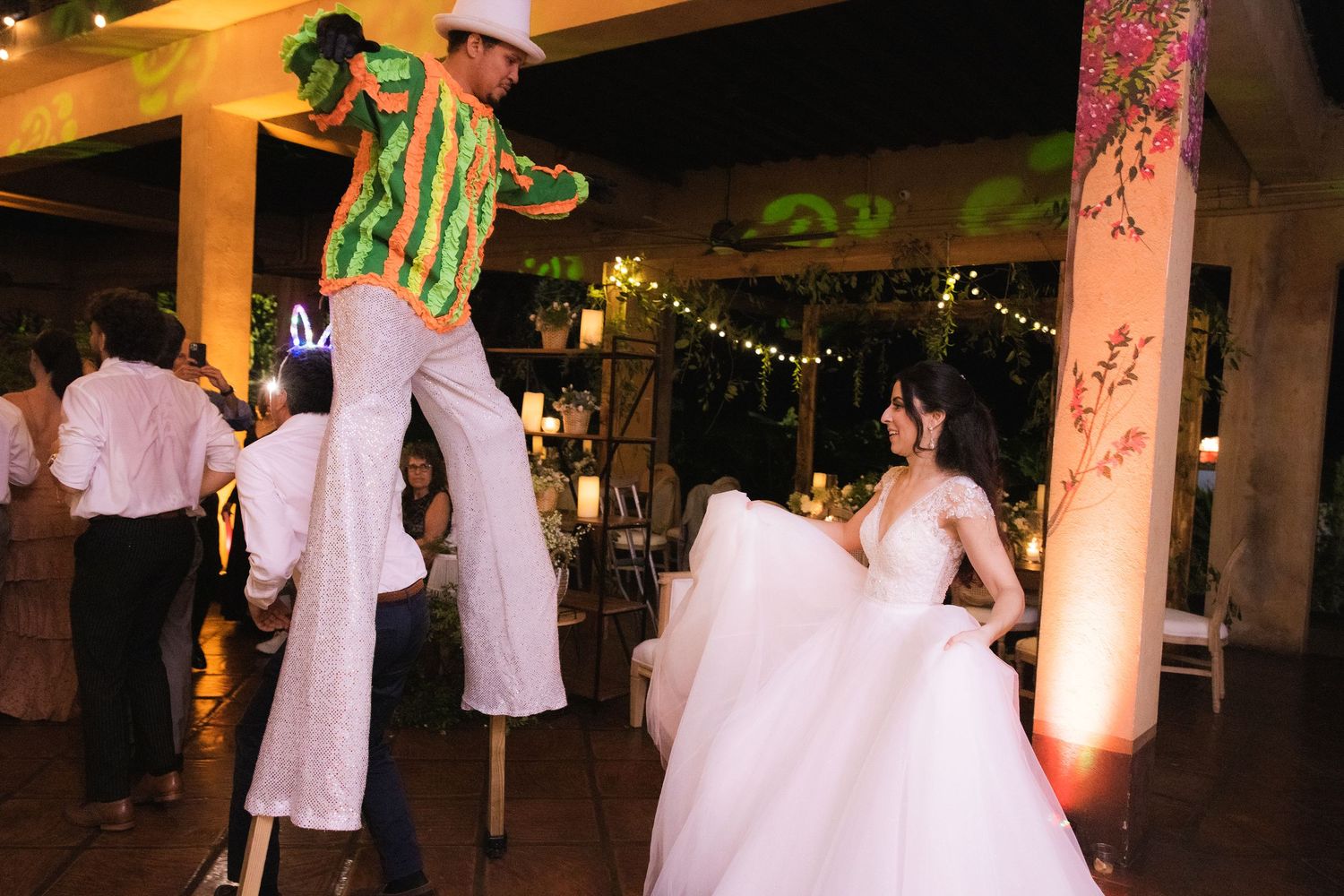 People dancing and celebrating at a nighttime wedding reception with string lights and decorative lighting.