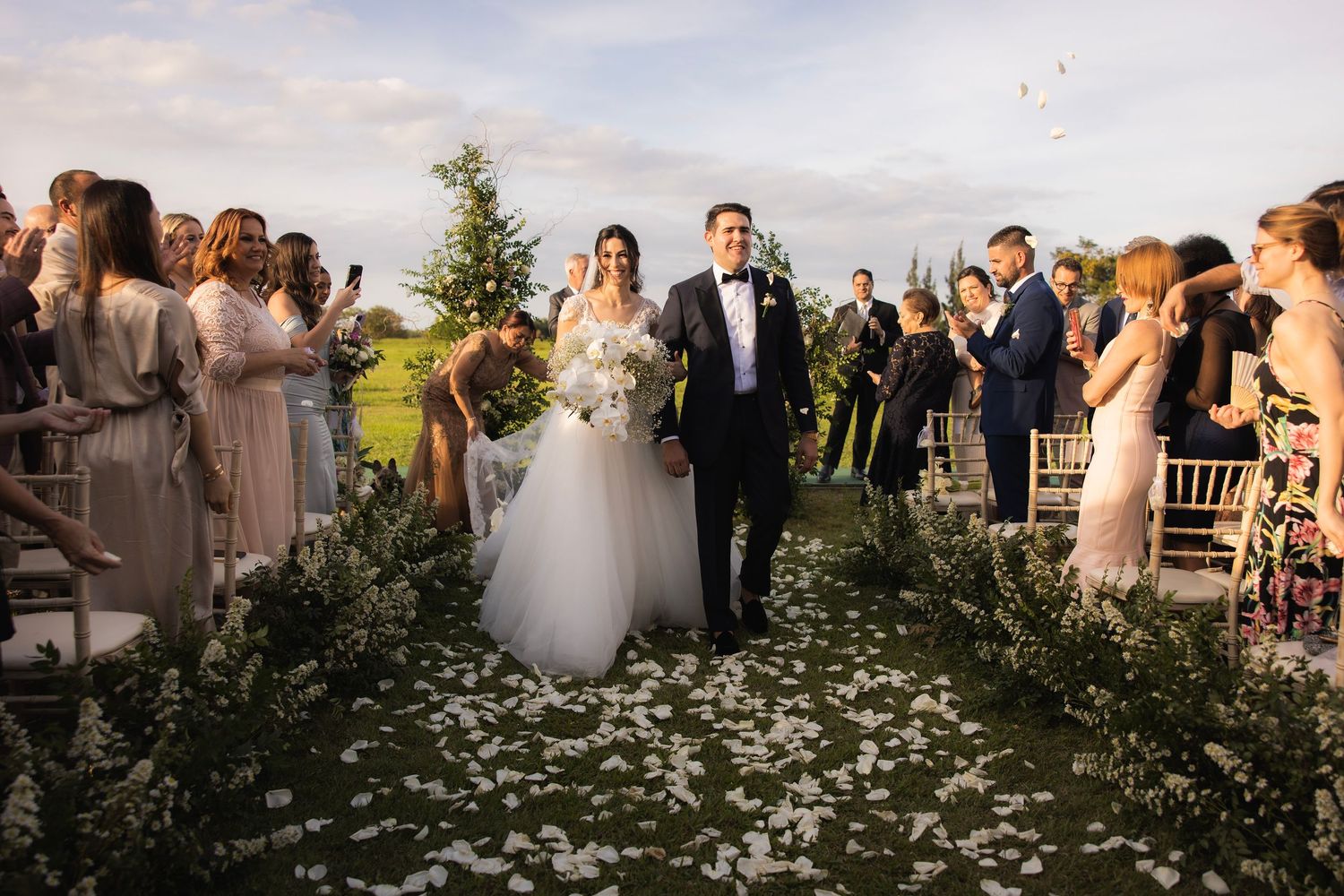 Wedding ceremony guests gather outdoors overlooking a scenic mountain landscape.