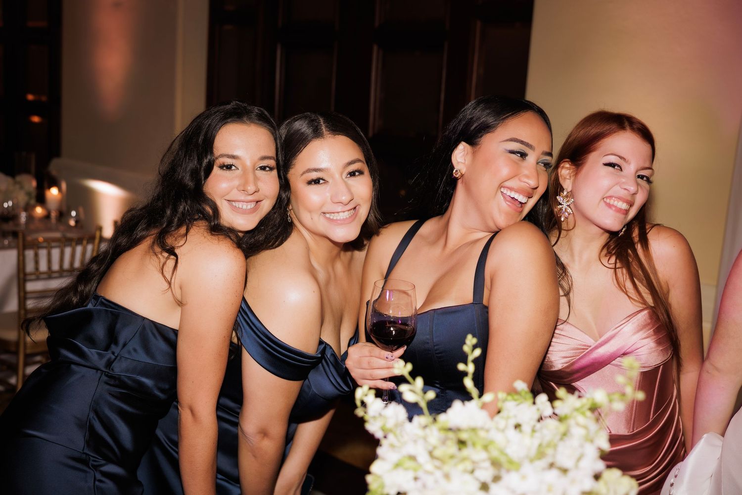 Group of women in formal attire laughing and enjoying themselves at an evening event.