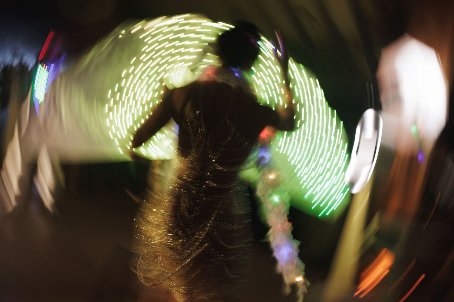 Green light trails create abstract patterns against a dark background at a nighttime event.