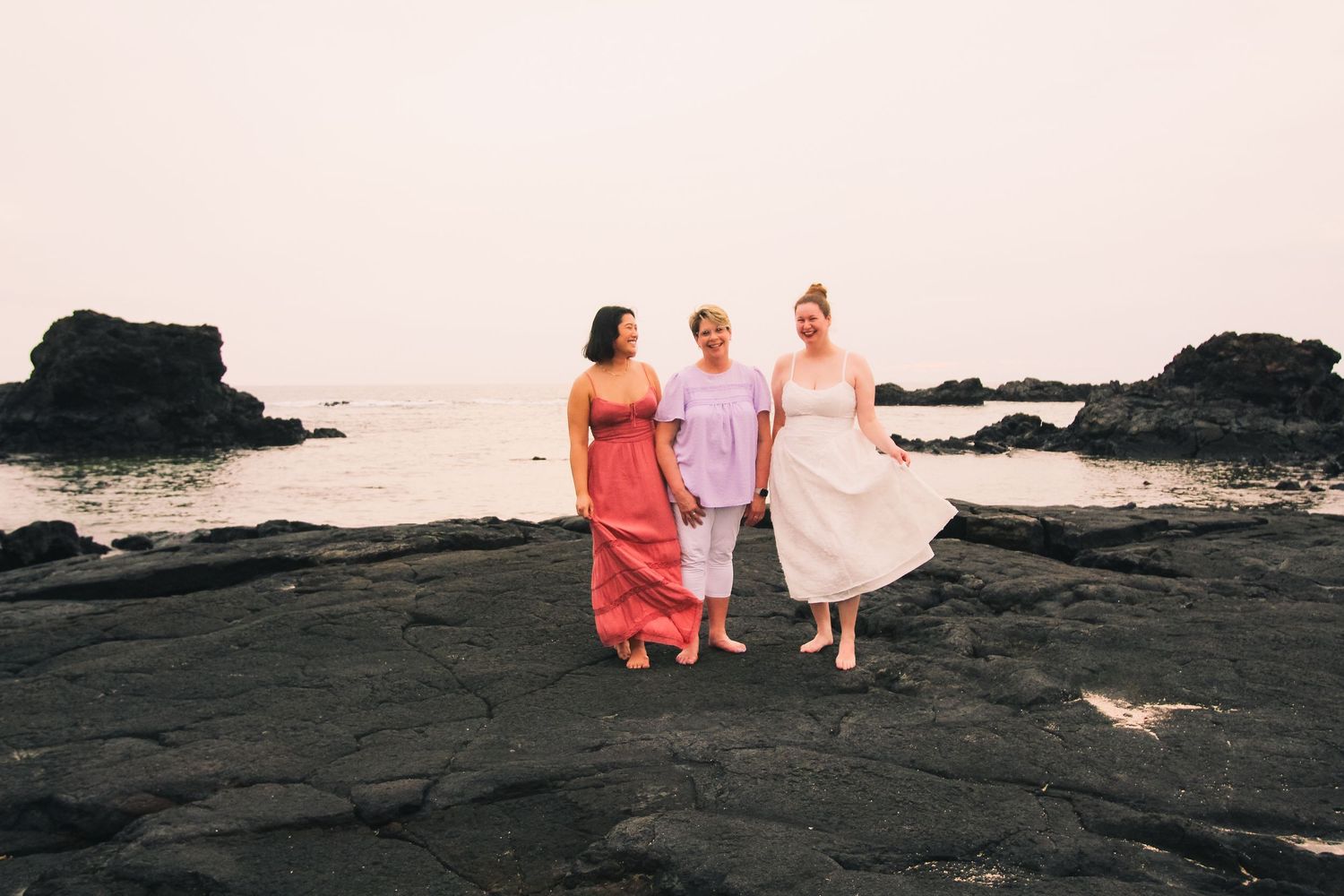 Golden hour family portrait of mother-in-law with two daughters-in-law on rocky coastline at Kaikaua Point Hawaii