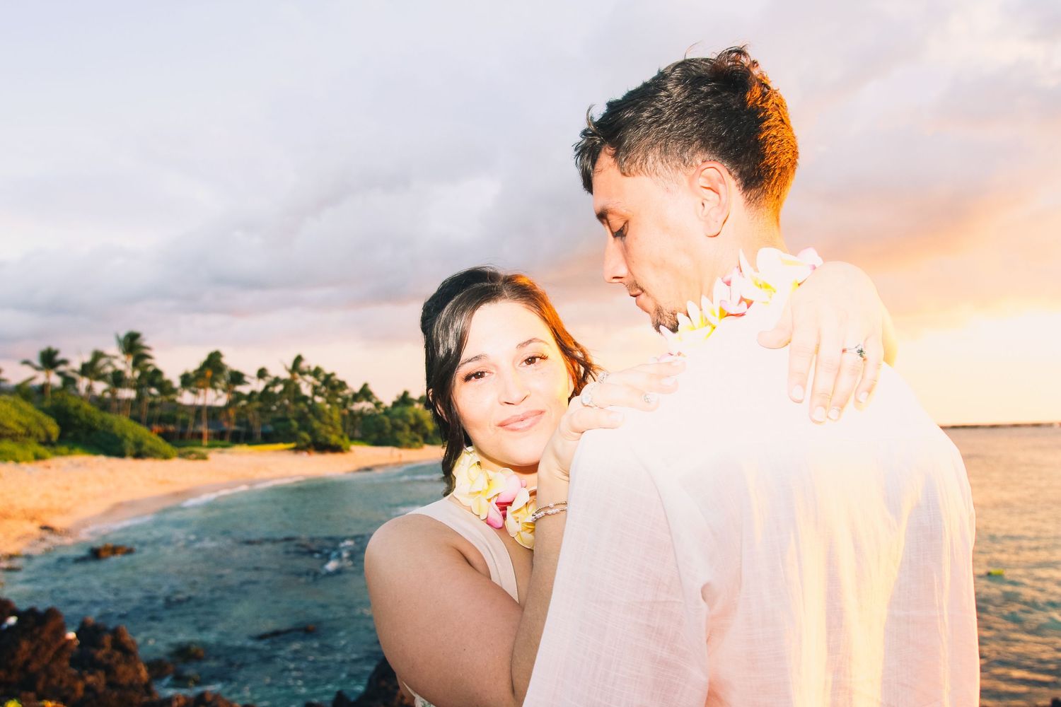 Newly married couple at Kukio Beach Hawaii elopement with groom looking down at bride in intimate moment at sunset