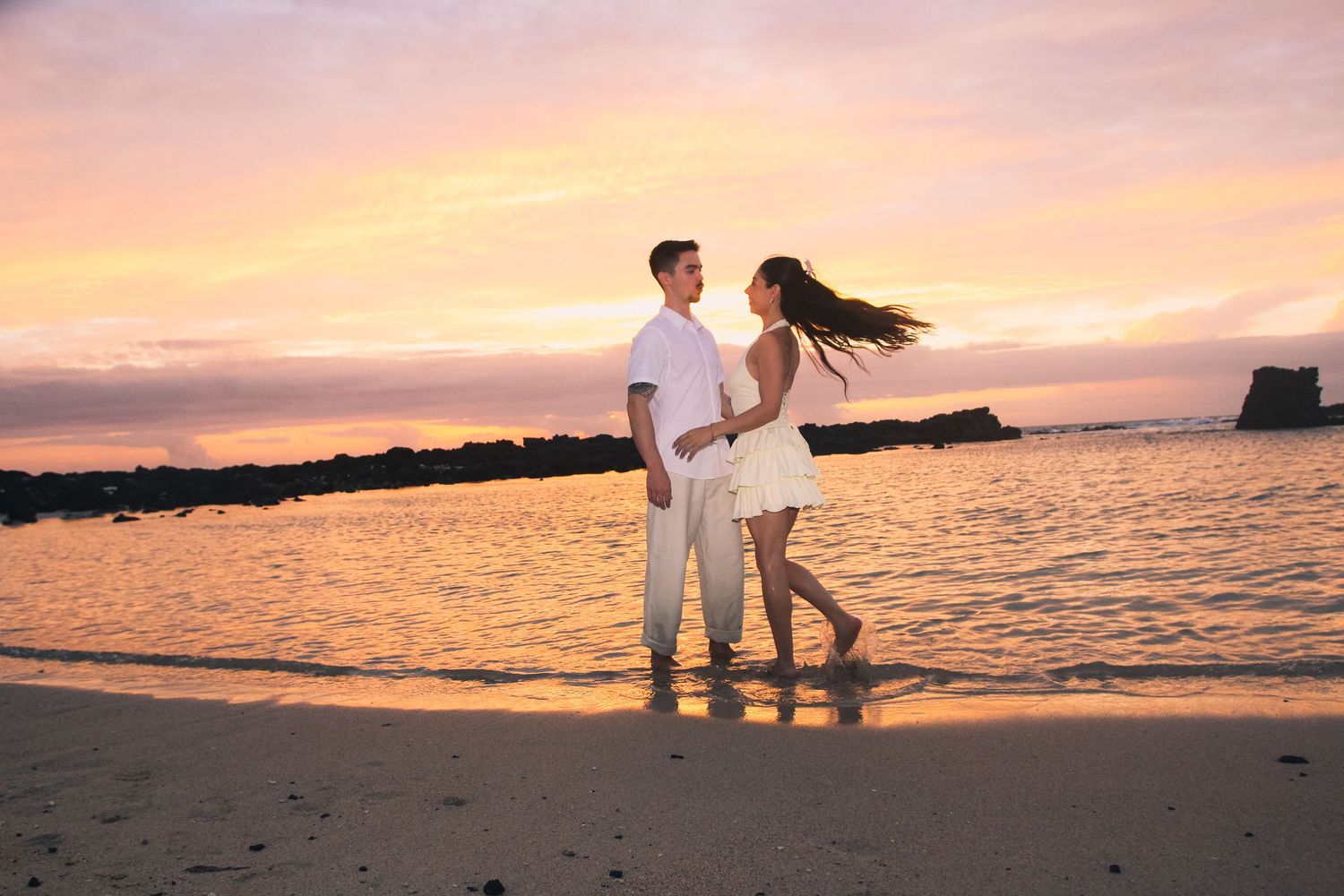 Romantic couple dancing by the water at golden hour sunset in Hawaii