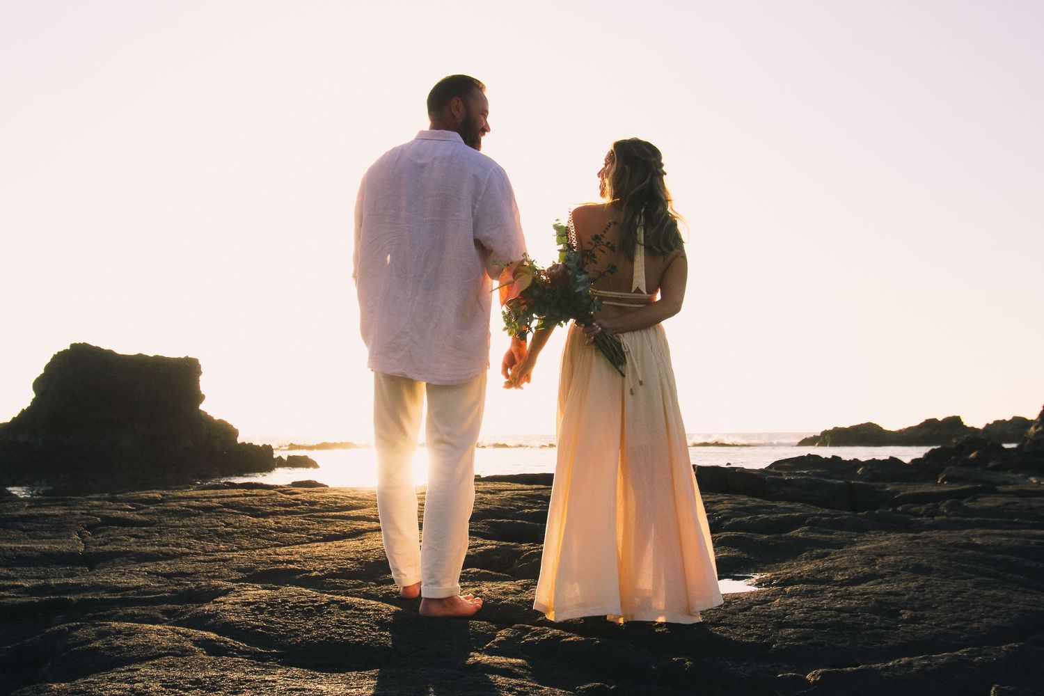 Couple standing on rocks at sunset at Kaikaua Point Beach Park Kona Hawaii with ocean backdrop