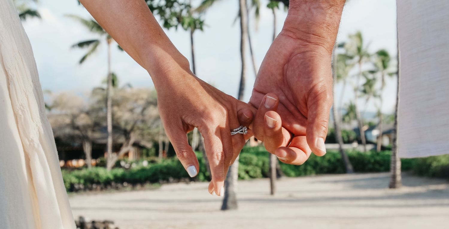 Close-up of couple holding hands showing wedding rings during sunset at Kaikaua Point Beach Park Kona Hawaii