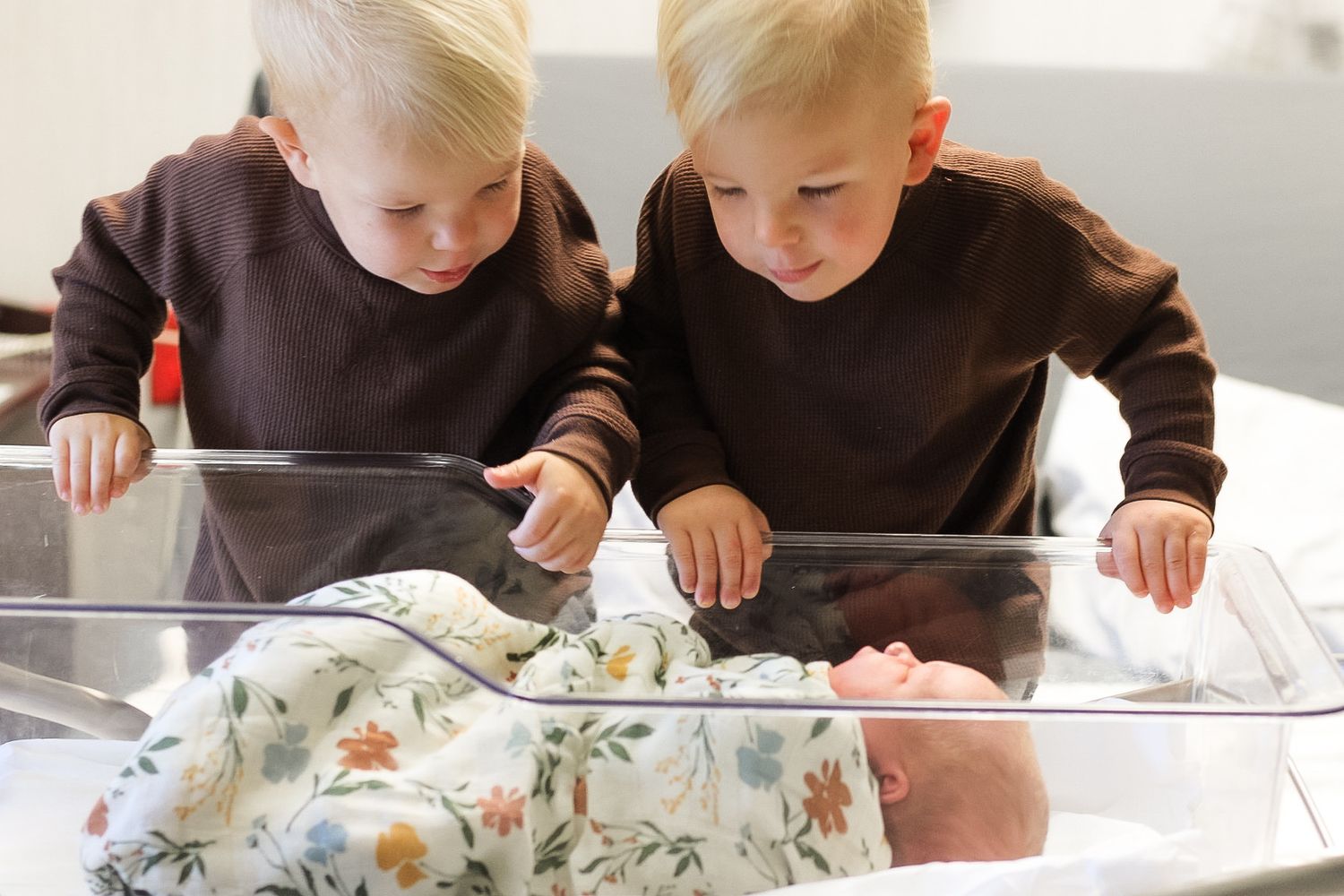 Twin two year old brothers look down on their brand new sister during their Fresh 48 session.