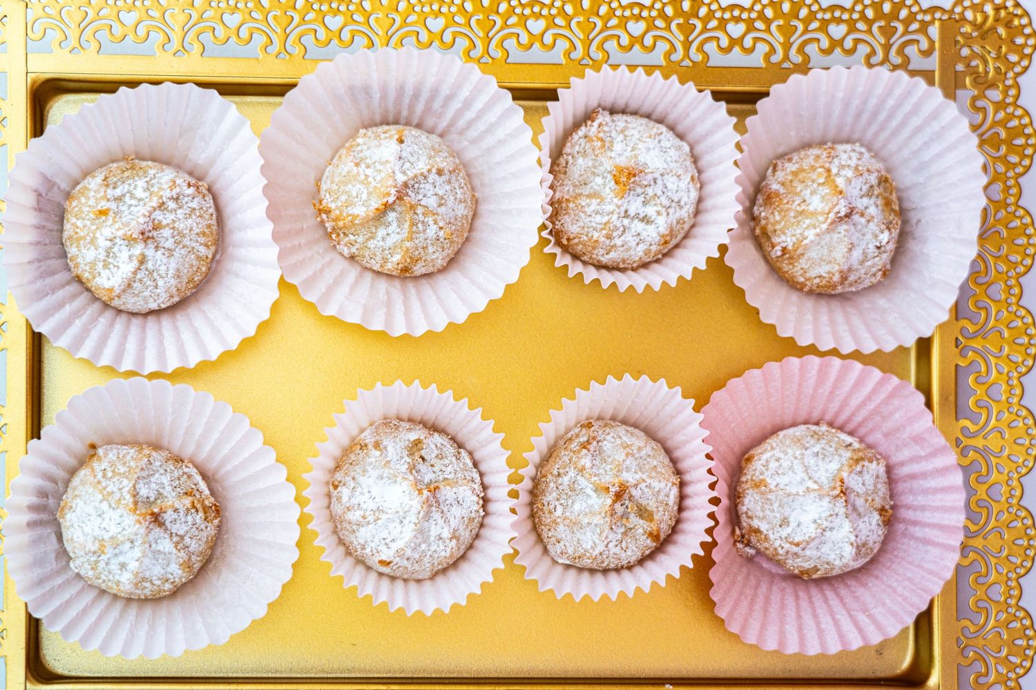 White paper doilies arranged with powdered desserts on a golden background.