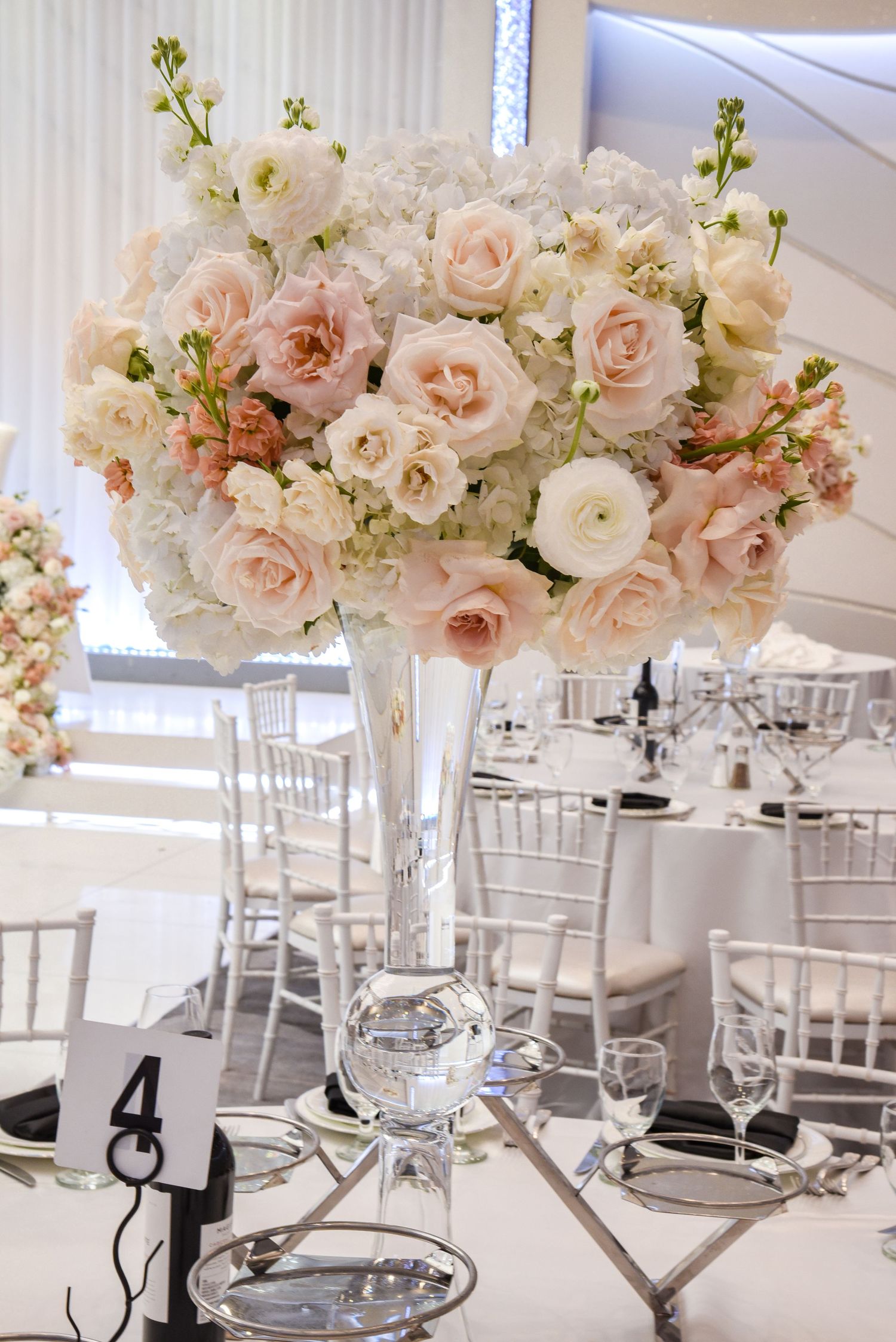 Romantic wedding reception tablescape with tall blush and white floral centerpieces and crystal elements.
