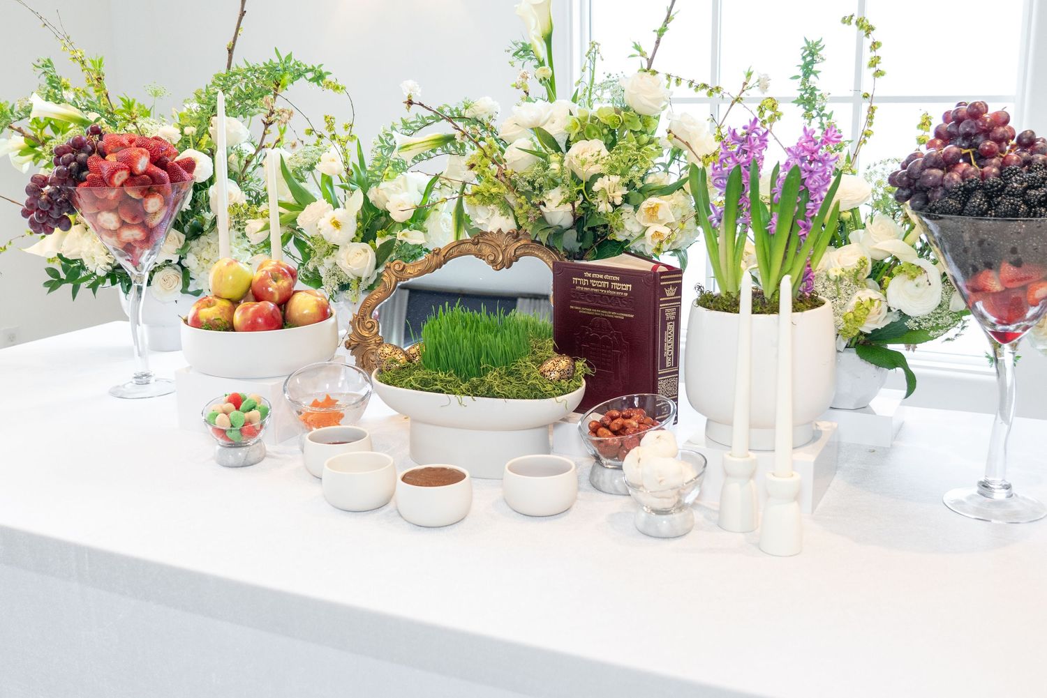 Colorful floral centerpieces and table decorations arranged on white surfaces.