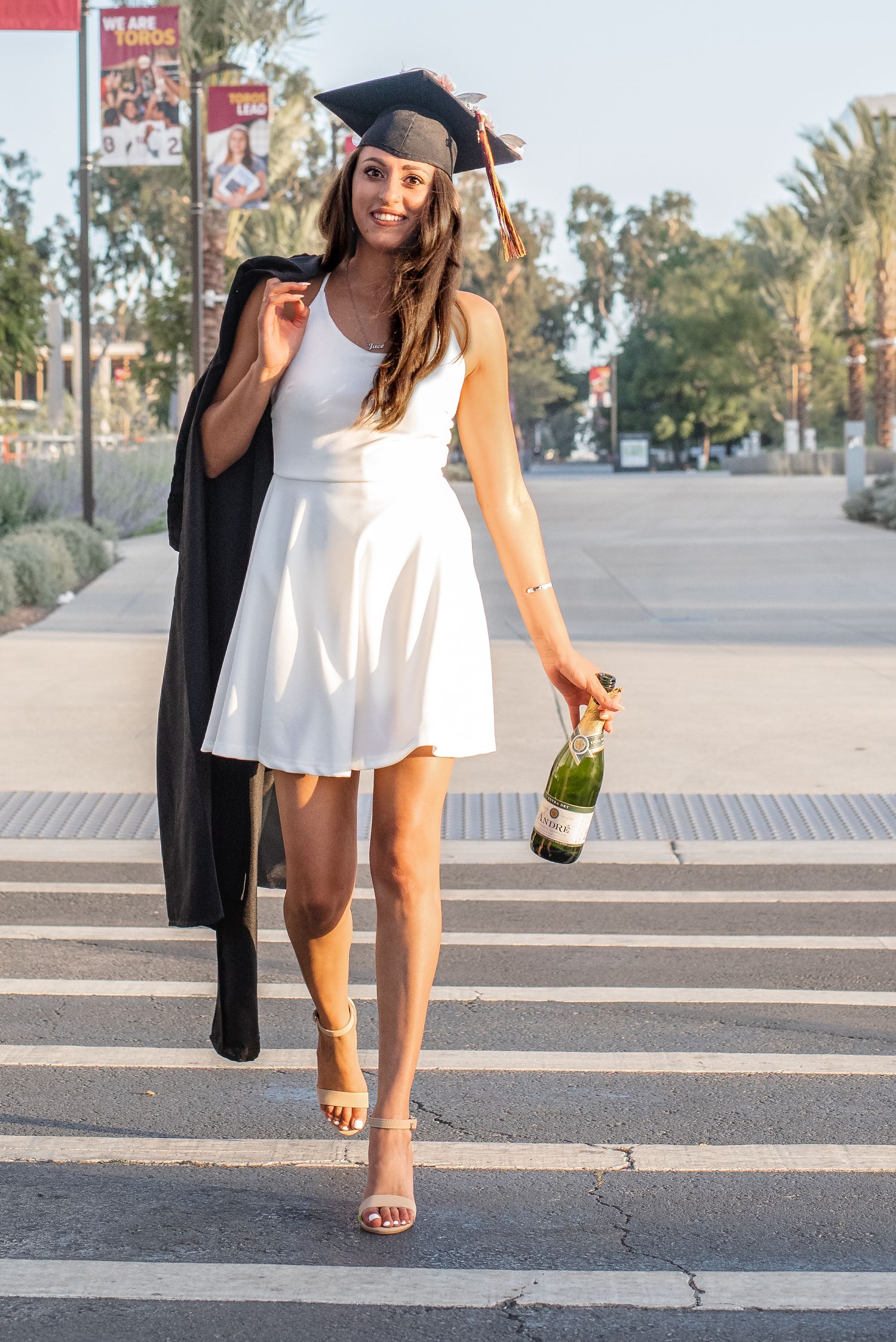 Low angle shots of graduate celebrating with champagne bottle.