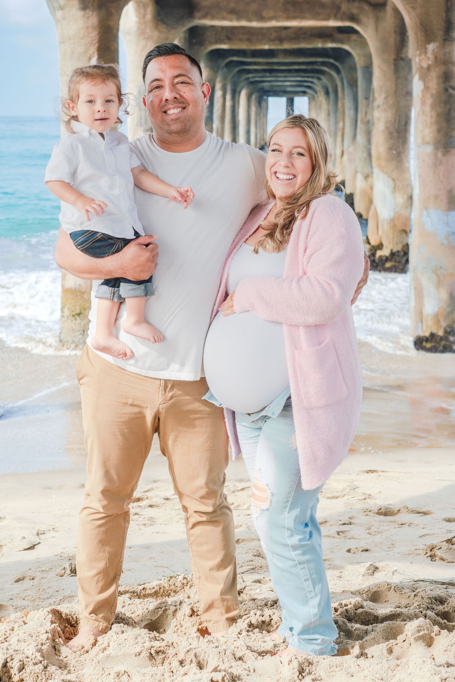 A family shares a joyful moment together under a beach pier.