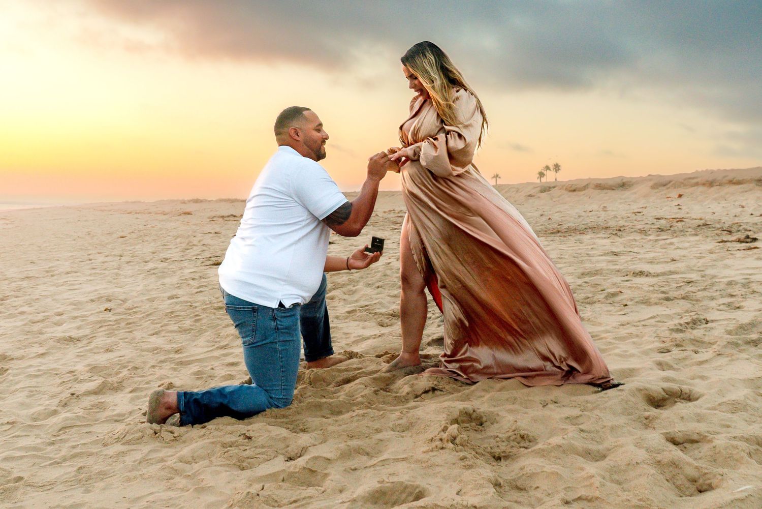 Beachside marriage proposal with flowing dress catching the sunset breeze.