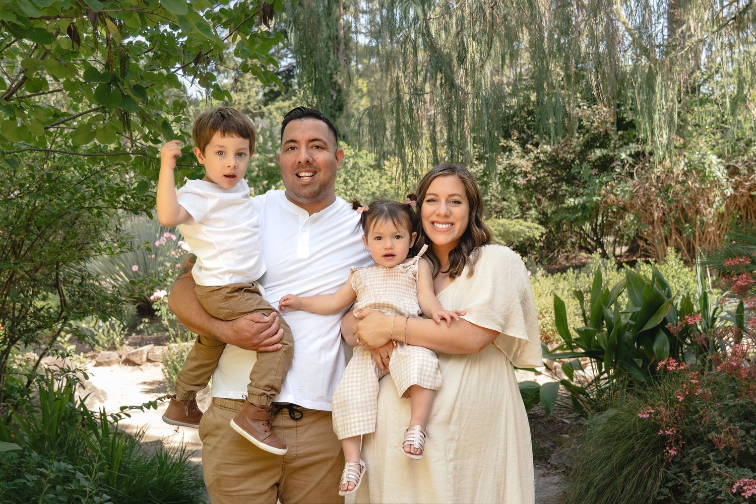 Outdoor family photography session in lush green garden setting with natural lighting.