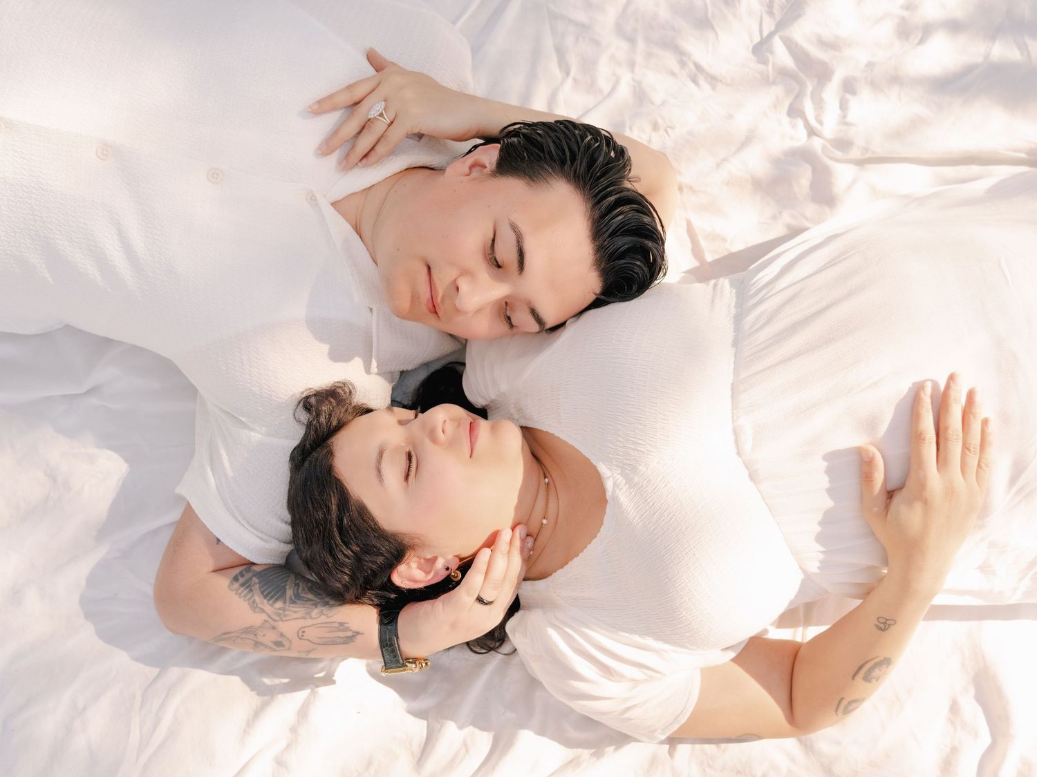 Intimate portrait of couple lying close together on white bedding.
